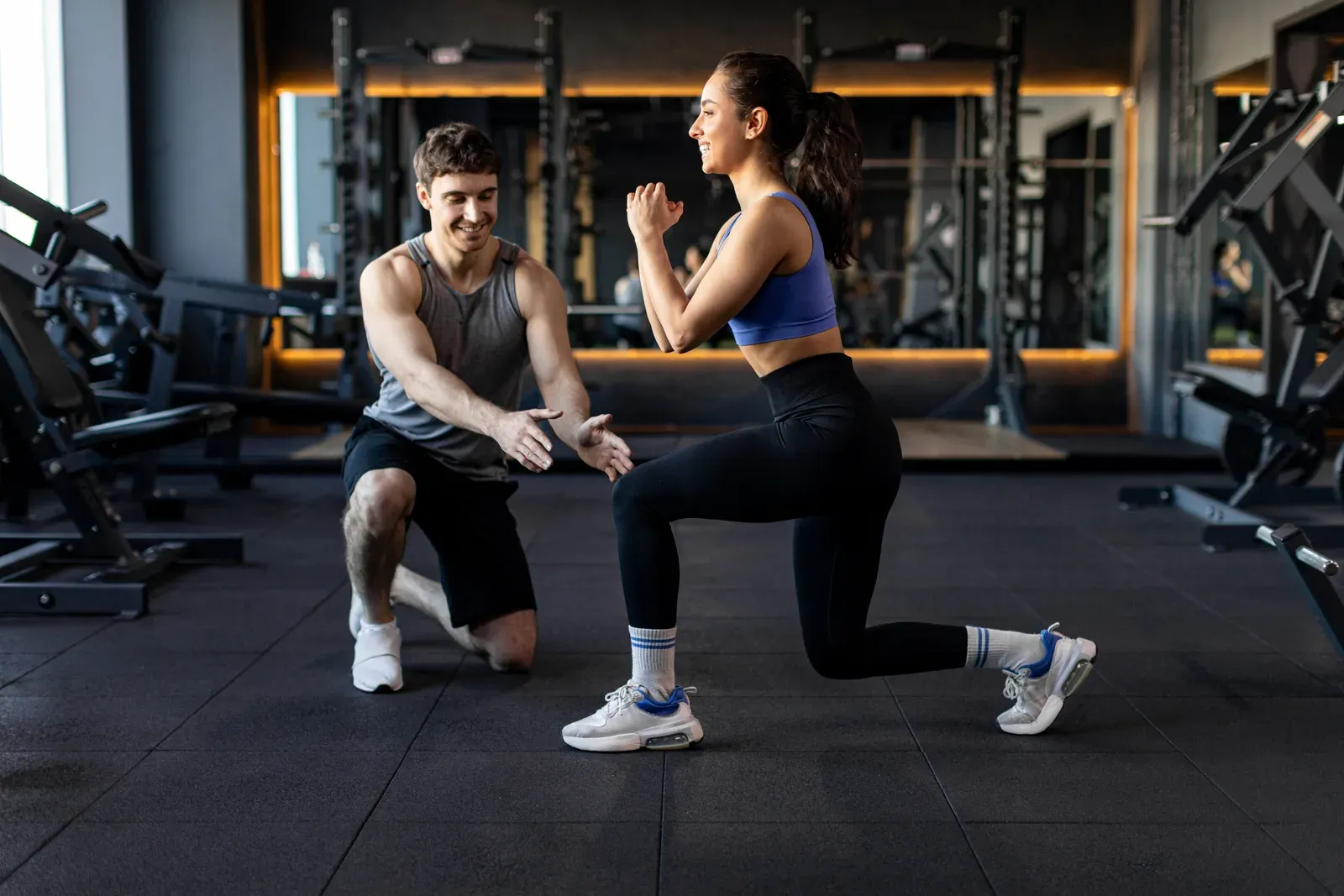 Personal trainer showing a sportswoman how to do lunges correctly, the kind of coaching a kickstart gives