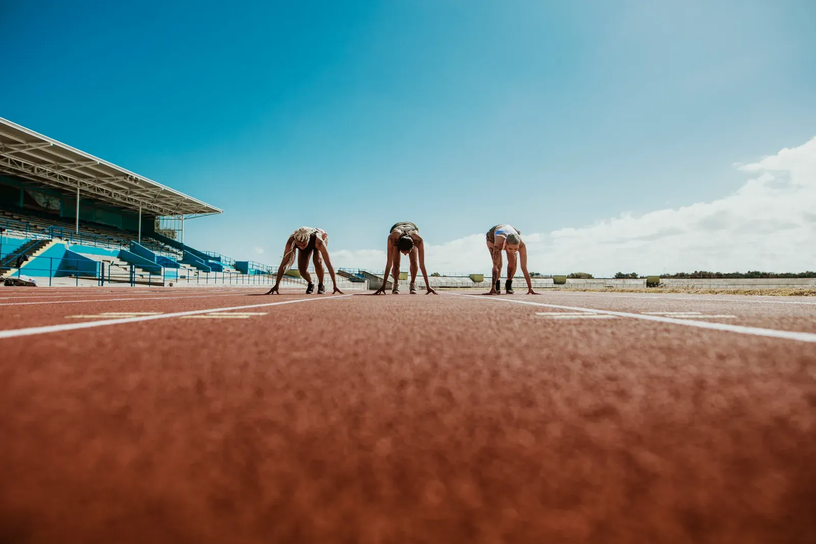 Athletes lined up at the starting line on a running track, the moment before a race distance begins