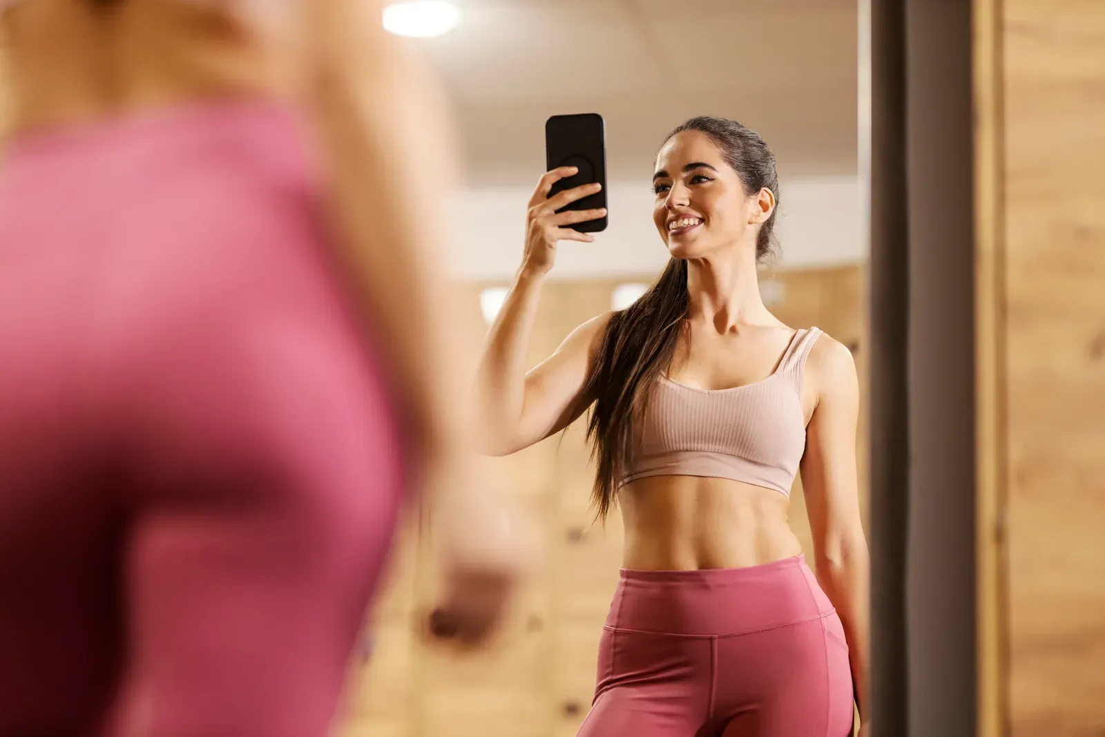 Sportswoman taking a gym mirror selfie to track her 90 day transformation progress