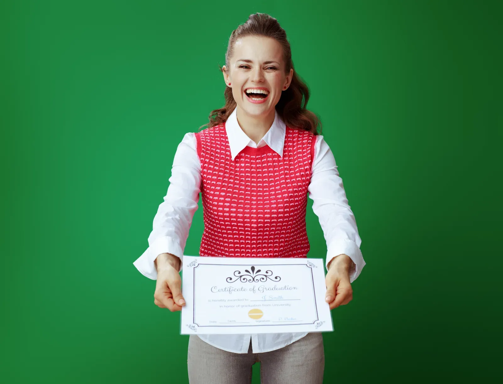 Smiling student woman holding up a certificate of graduation, a credential like a trainer certification
