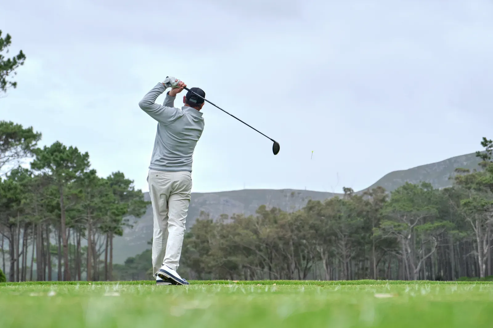 A golfer over 50 finishing a full driver swing on the tee