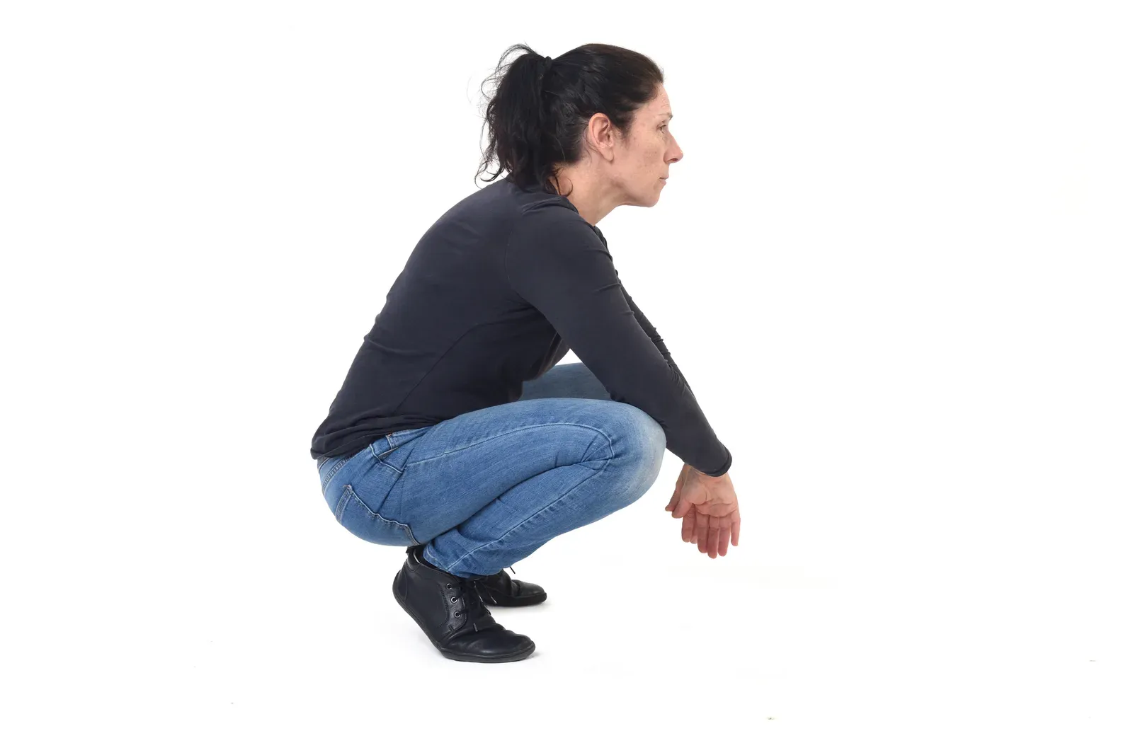 Side view of a woman squatting against a white background, showing the position ankle mobility affects