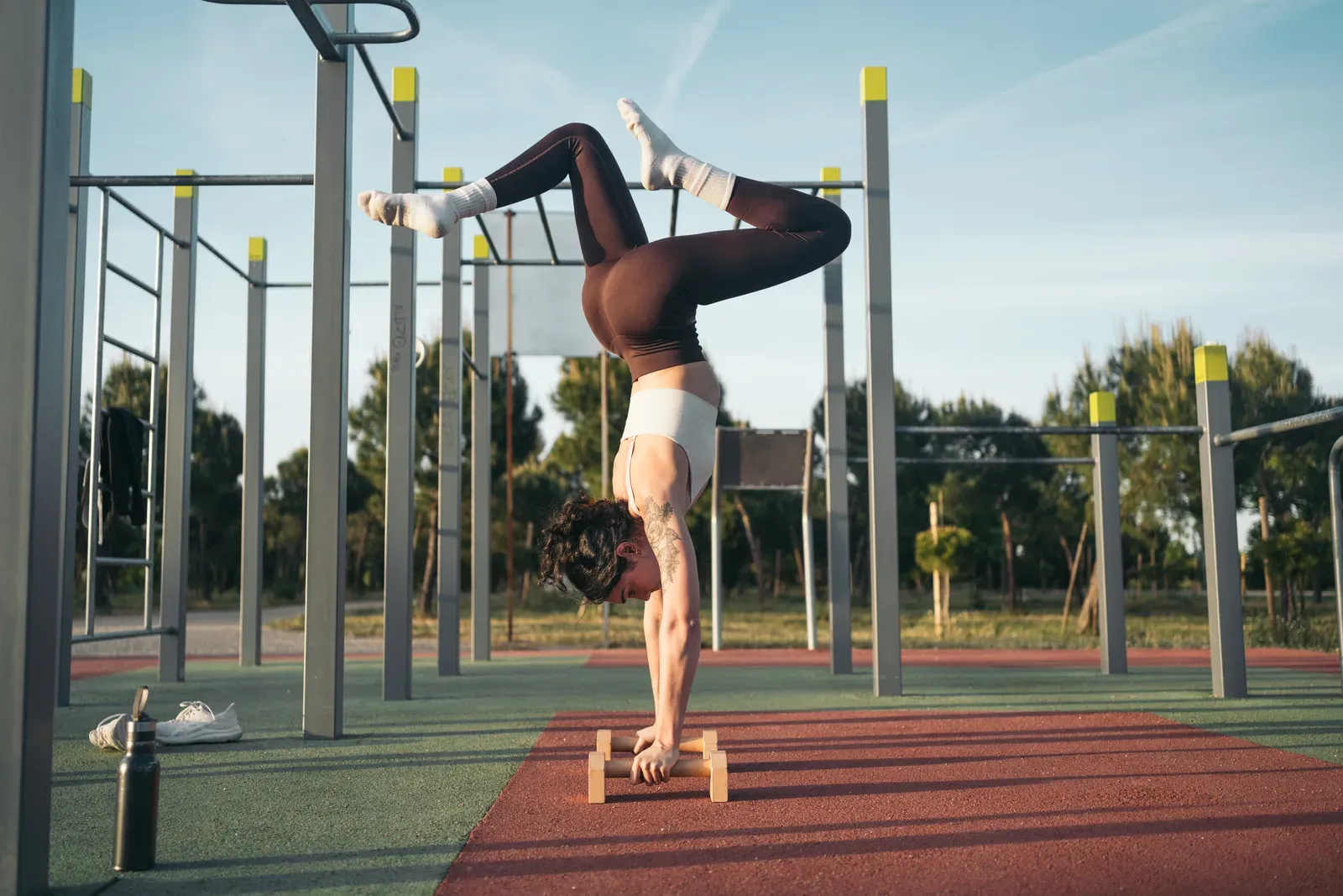 Woman practicing calisthenics outdoors on a sunny day, an active adult training at her own body weight