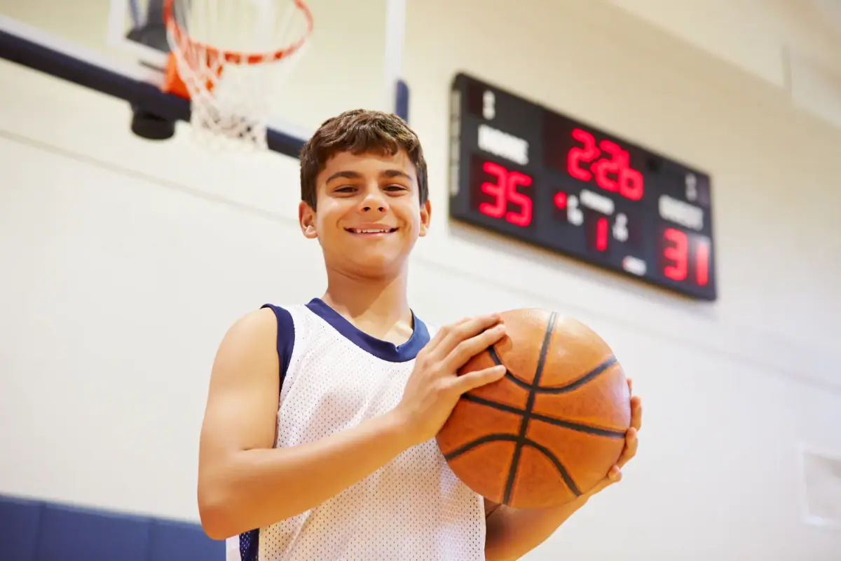 Basketball player elevating toward the rim inside an indoor gym