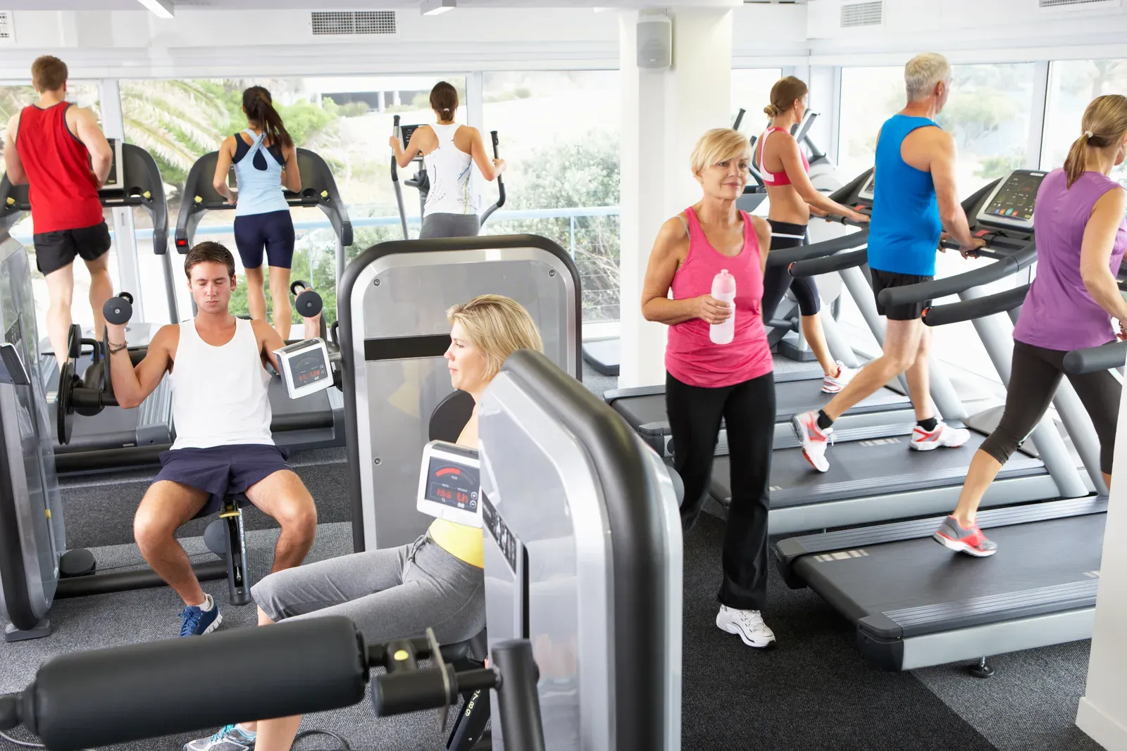 A woman training with dumbbells in a calm, warmly lit gym on a winter evening