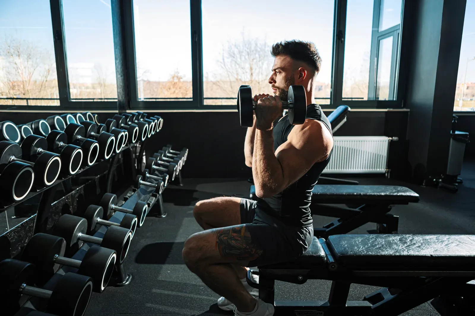 Young man building strength with dumbbells on a bench, the kind of pressing work behind a bench plateau