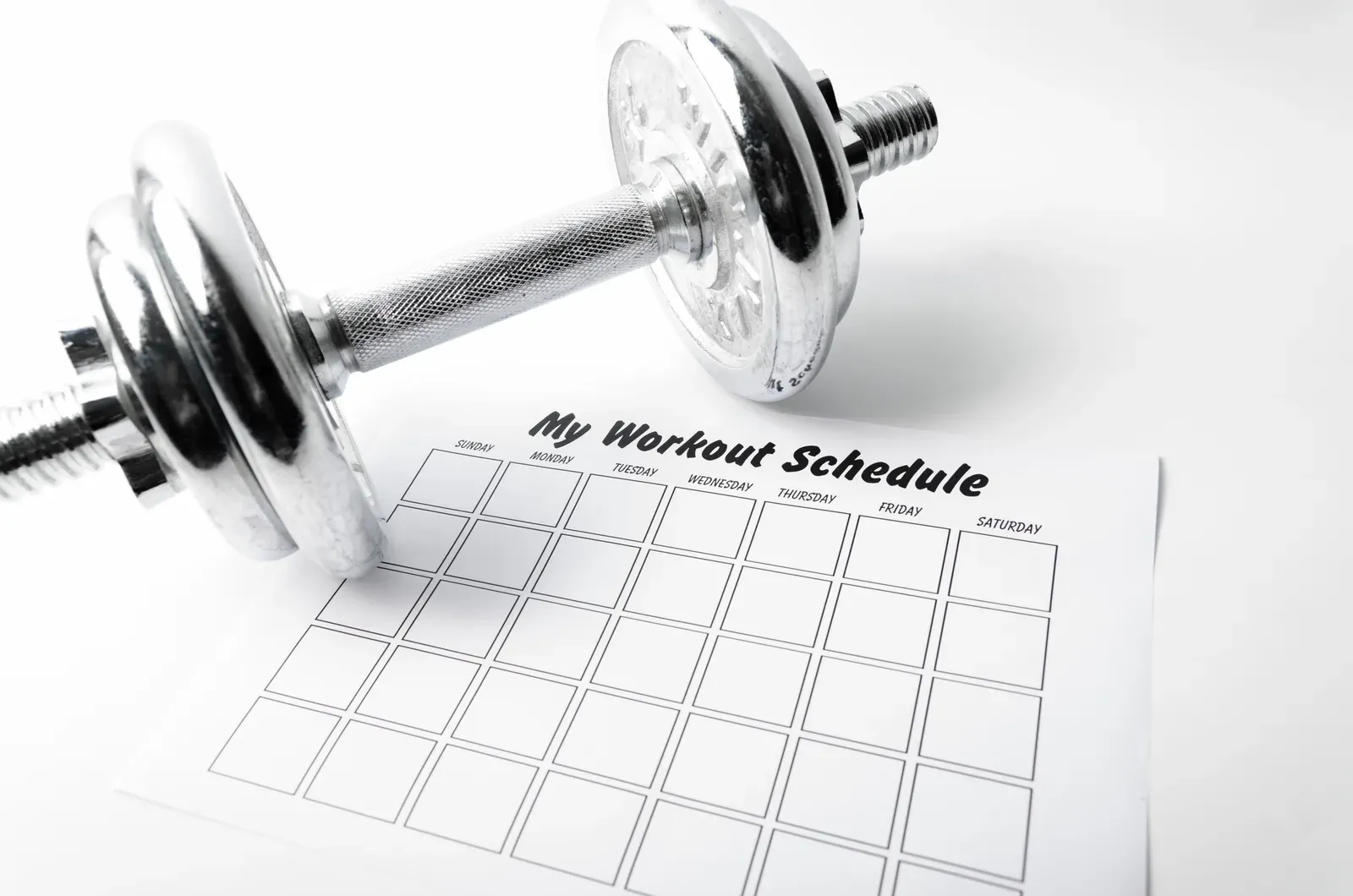 Workout schedule sheet with a dumbbell on a white background, planning the best days of the week to lift