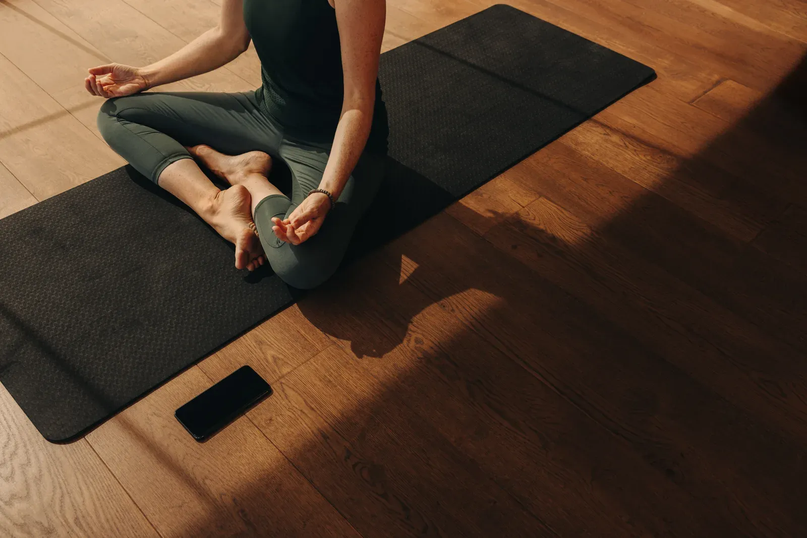 Woman doing hatha yoga at home, a quiet option for introverts who find busy gyms draining