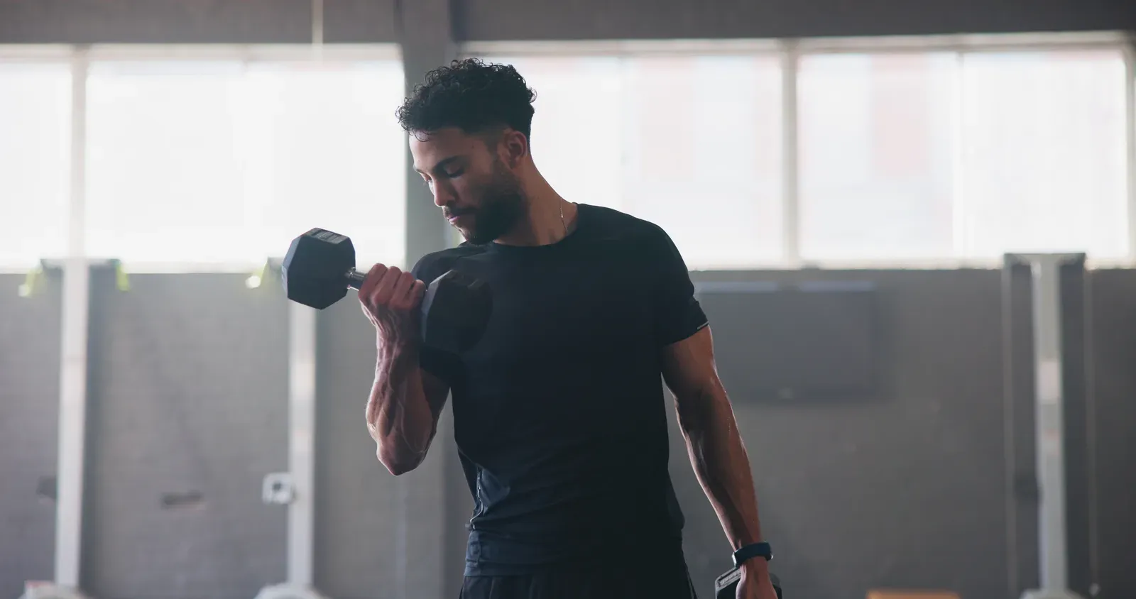Man in the gym with dumbbells, showing the kind of strength work where rep range choices come up