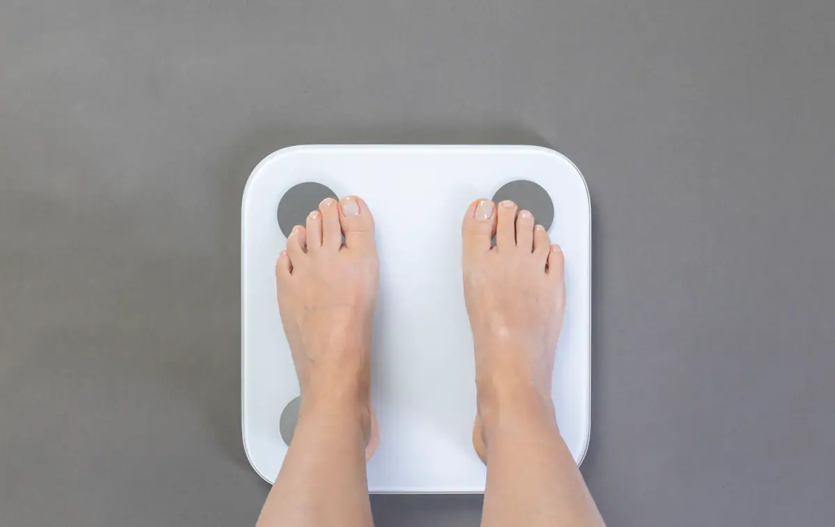 A person stepping onto a professional body composition analyzer in a fitness studio