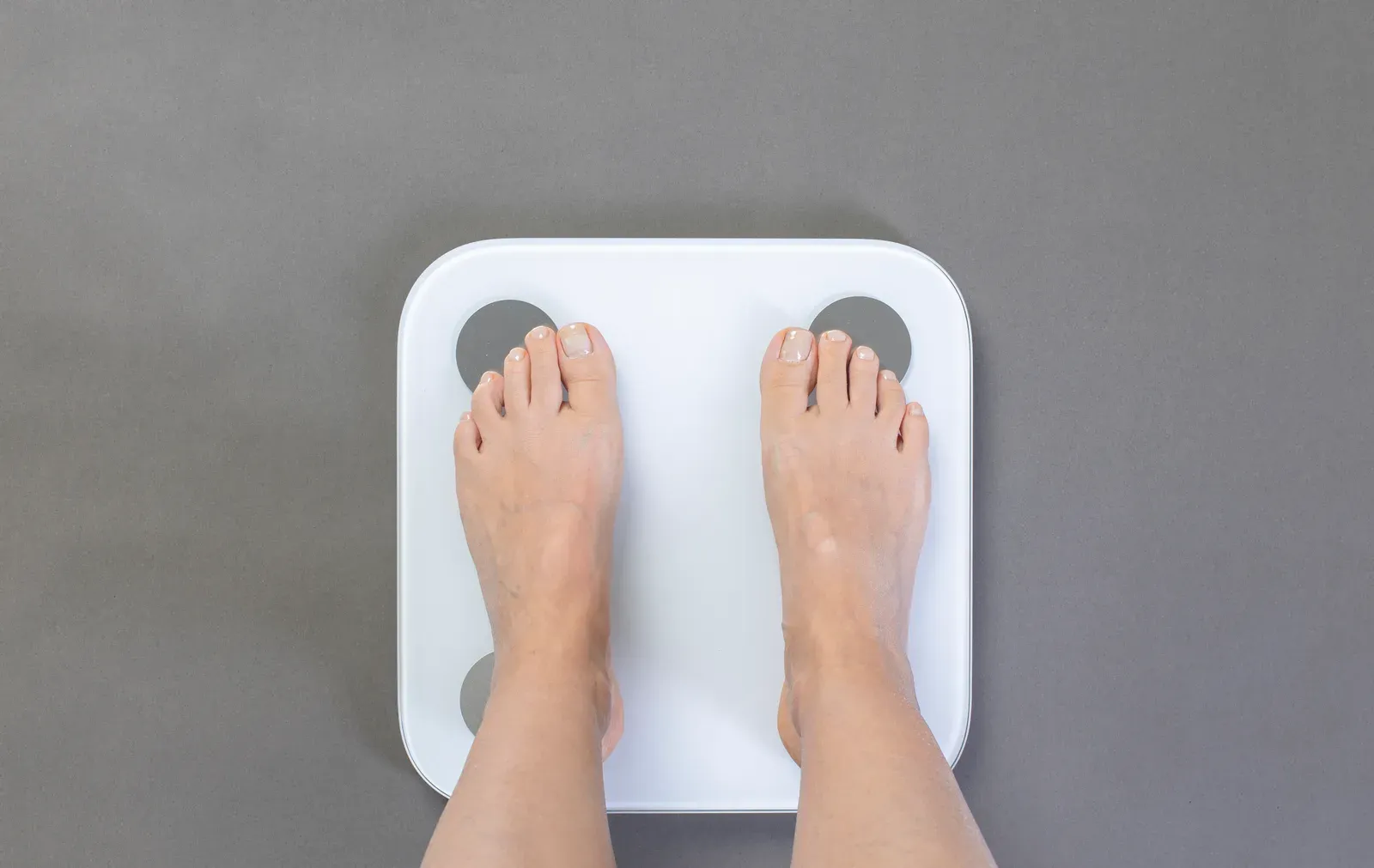 A person stepping onto a professional body composition analyzer in a fitness studio