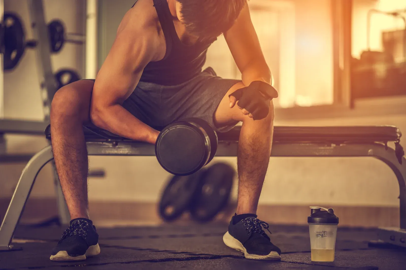Bodybuilder working out with dumbbells at the gym, illustrating the build muscle or cut first question