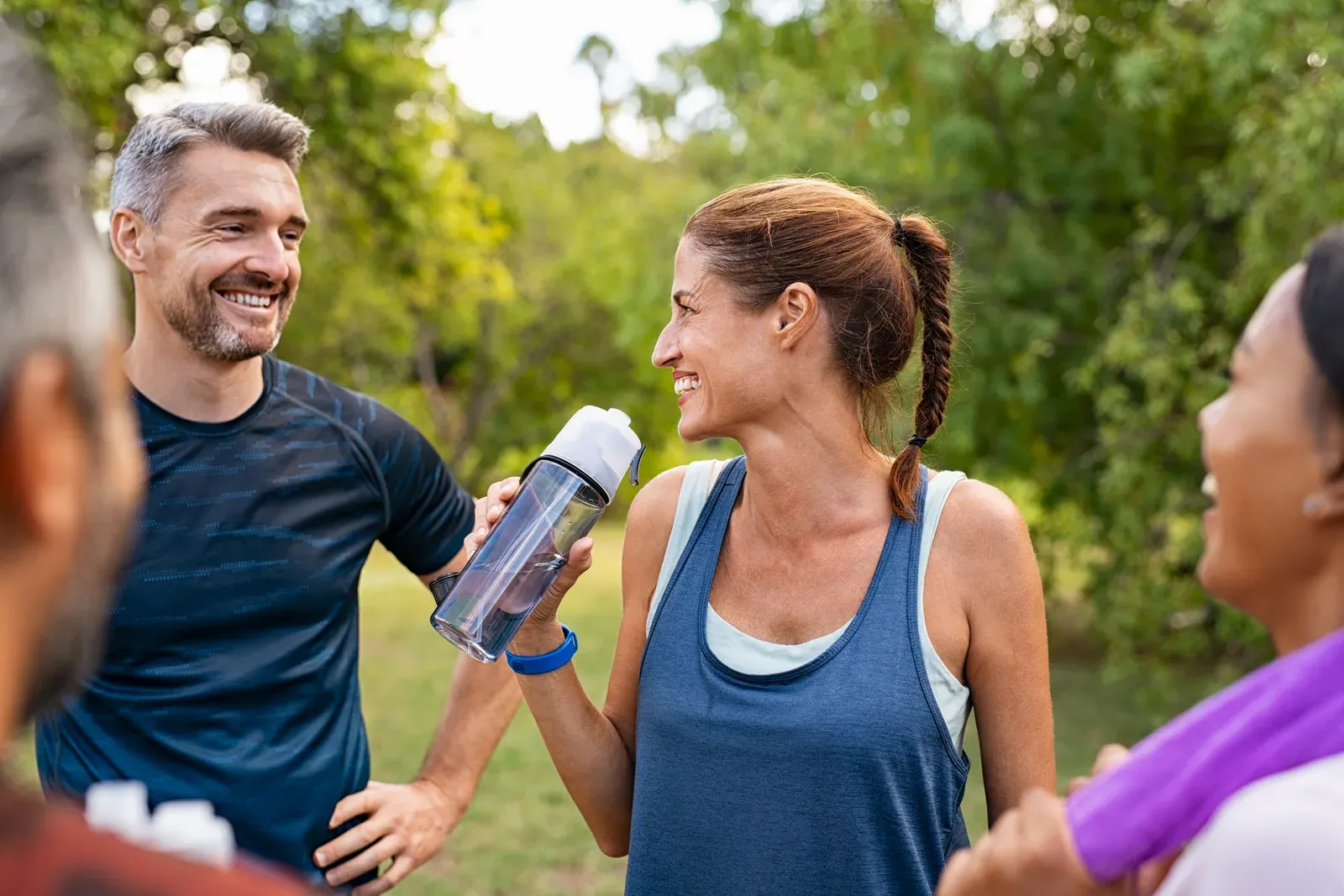 Mature woman drinking water after a workout, a reminder of how hydration relates to body water readings