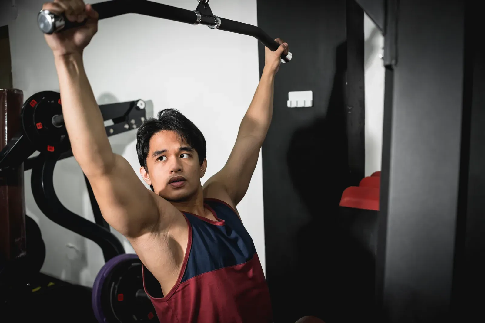 Young man doing lat pulldowns at the gym, a back exercise for building a wider back