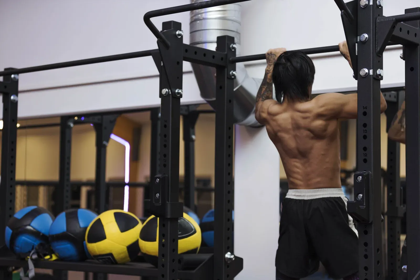 Close view of a man doing pull-ups, a bodyweight staple in the calisthenics versus weights choice