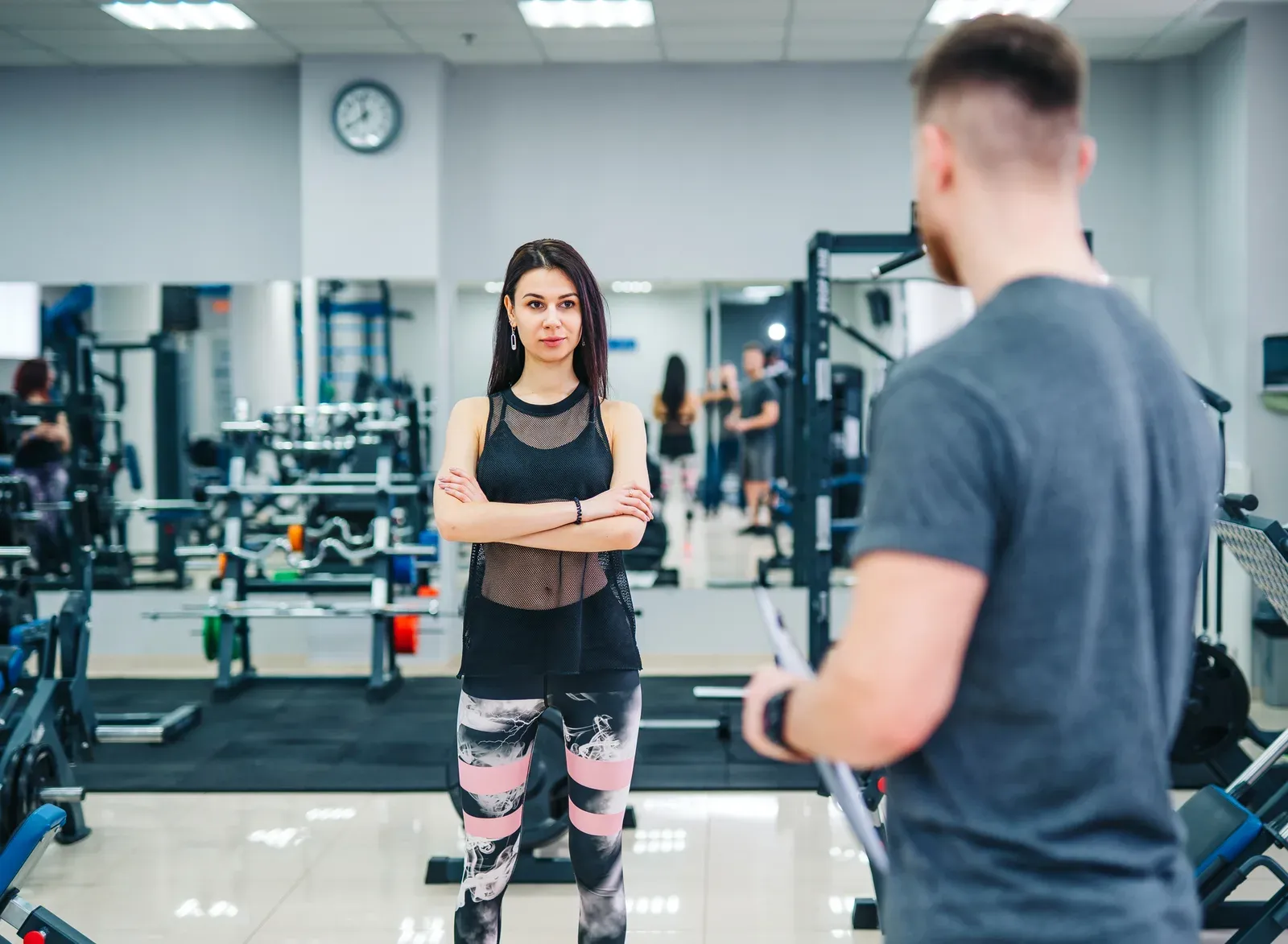 Trainer and client discussing her progress at the gym, a chat that fits a pre-signup session visit