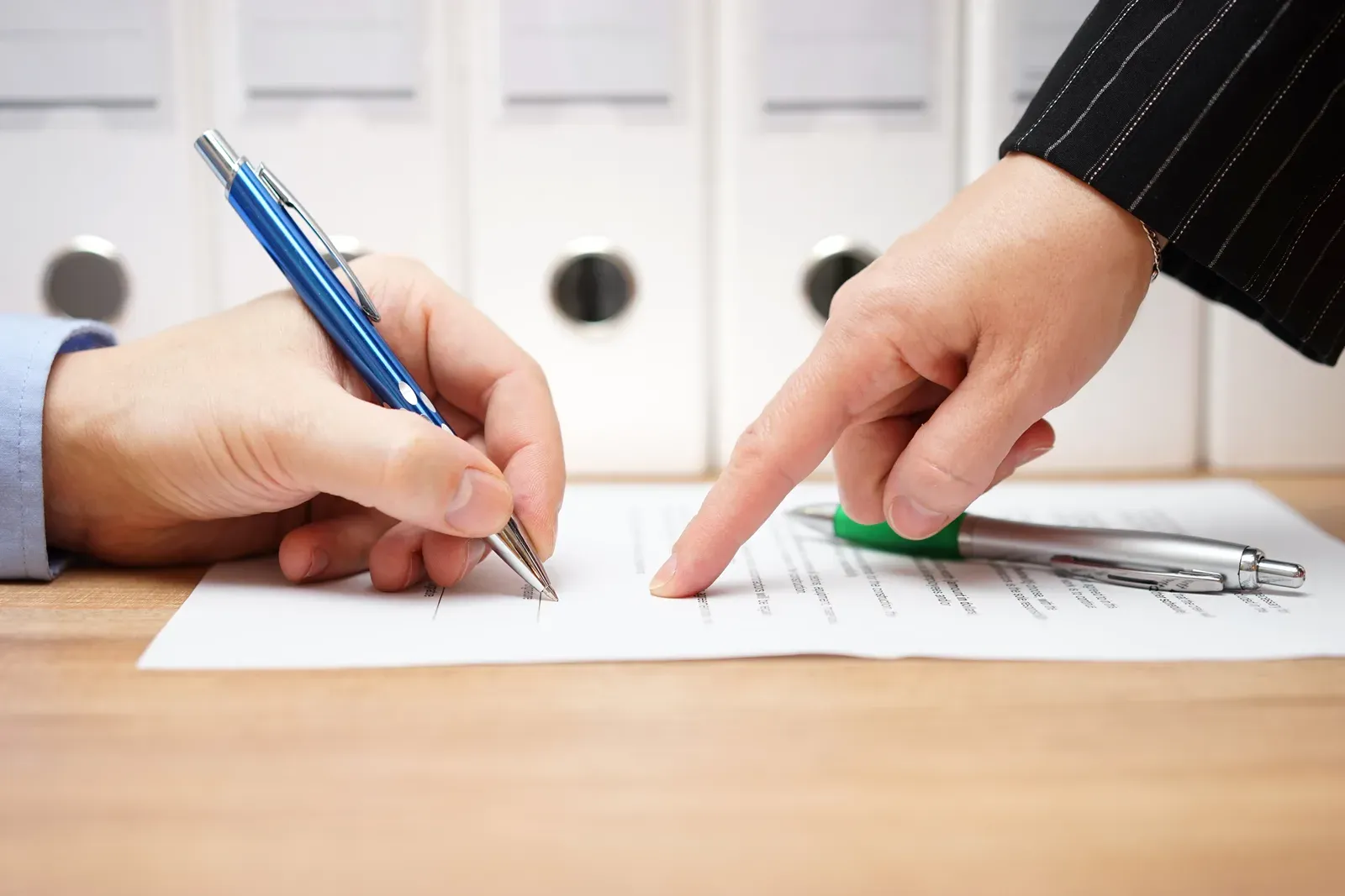 Business woman pointing to where to sign on a document, as in reviewing a gym contract before cancelling