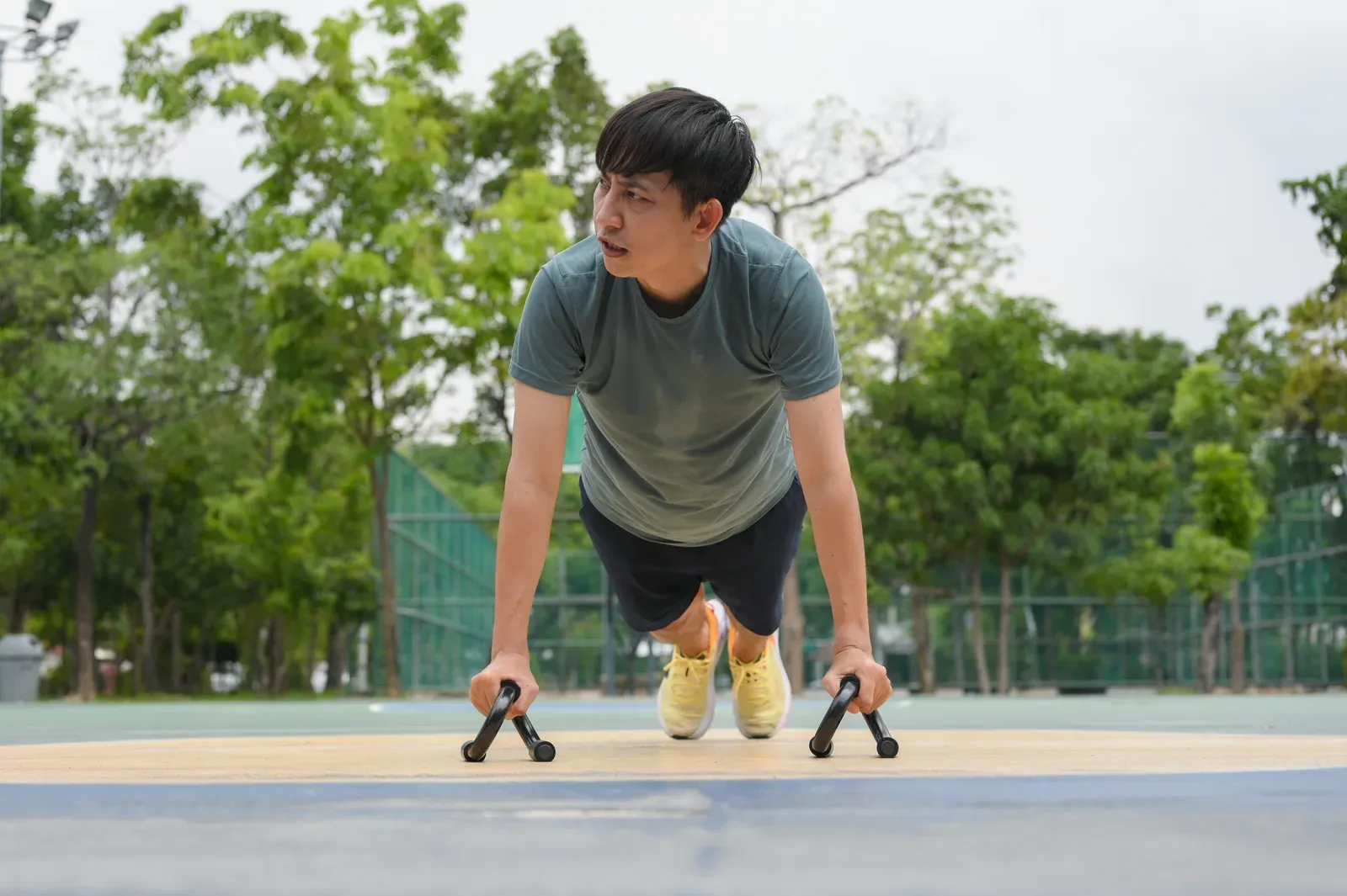 Young man in sports clothes exercising in a park sports field, an easy place to start your first session
