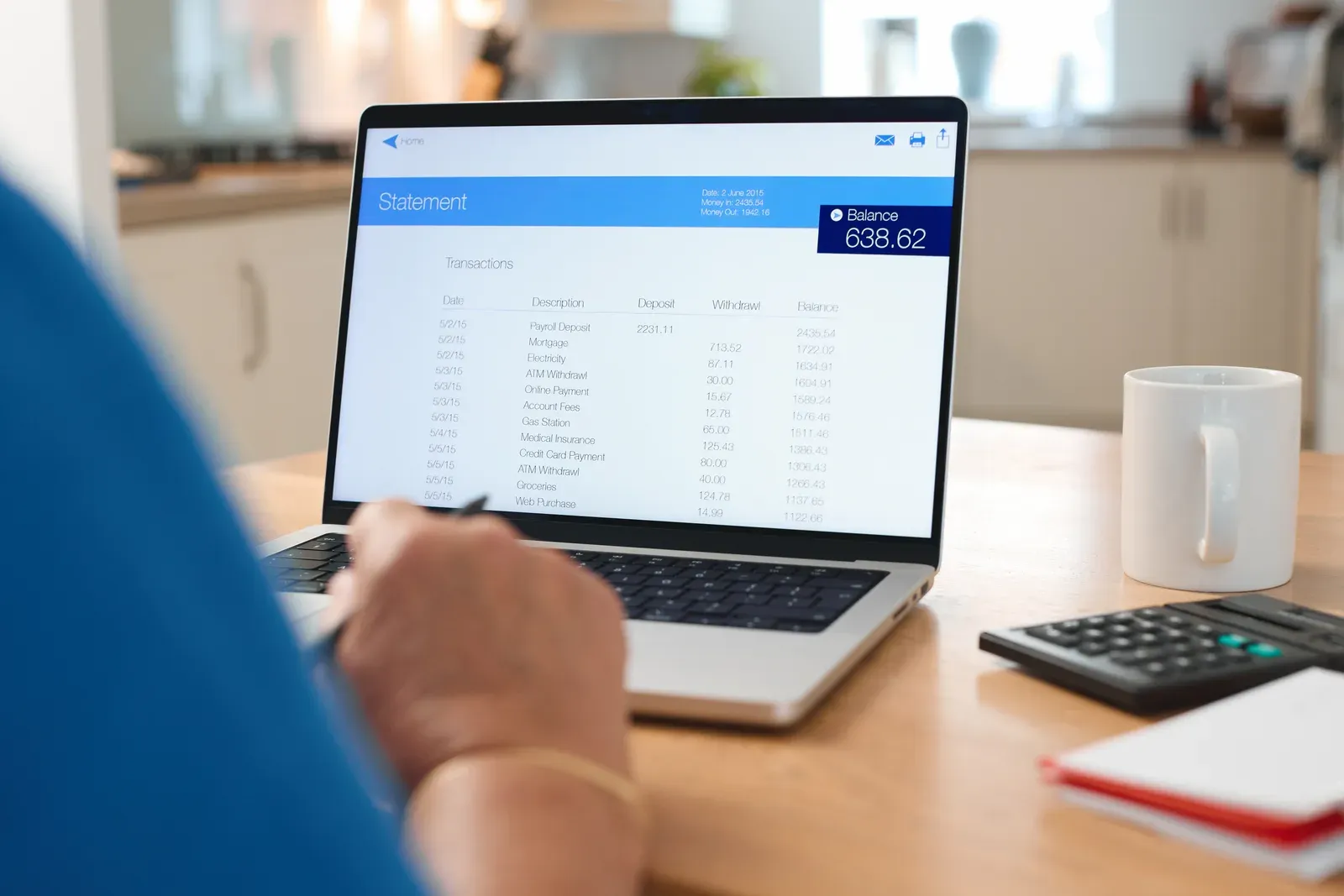 Person reviewing a bank statement on a laptop in a modern kitchen, a step when checking charges after cancelling