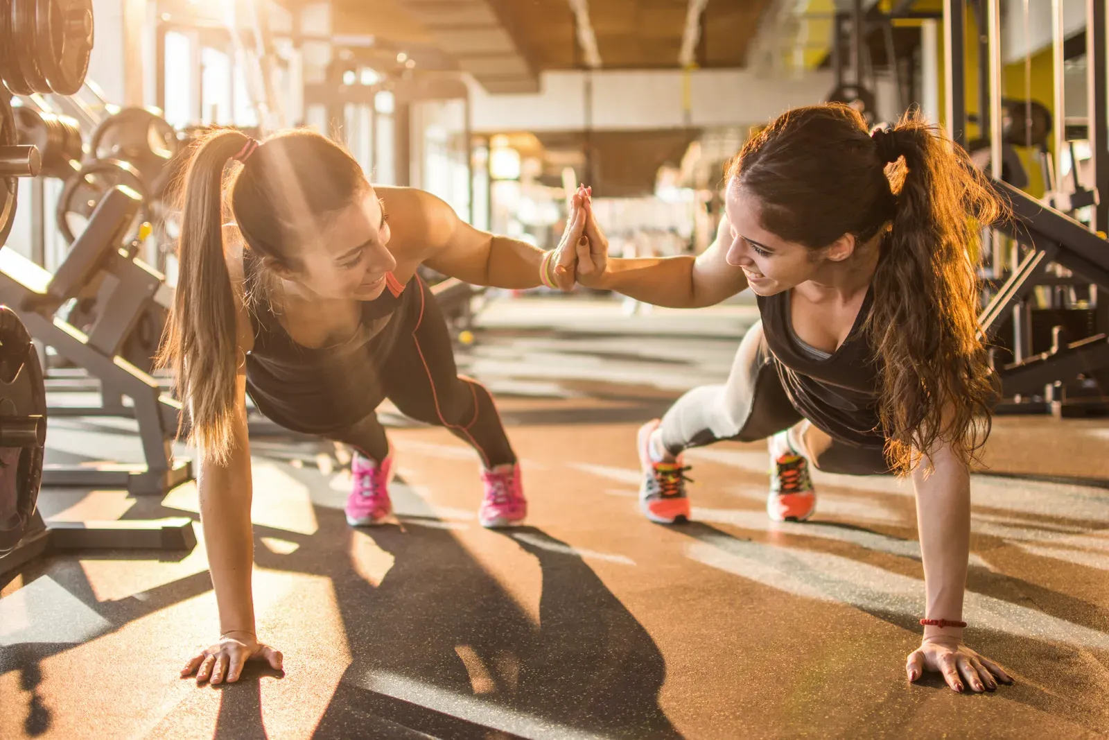 Two women exchanging a high five during a gym workout together