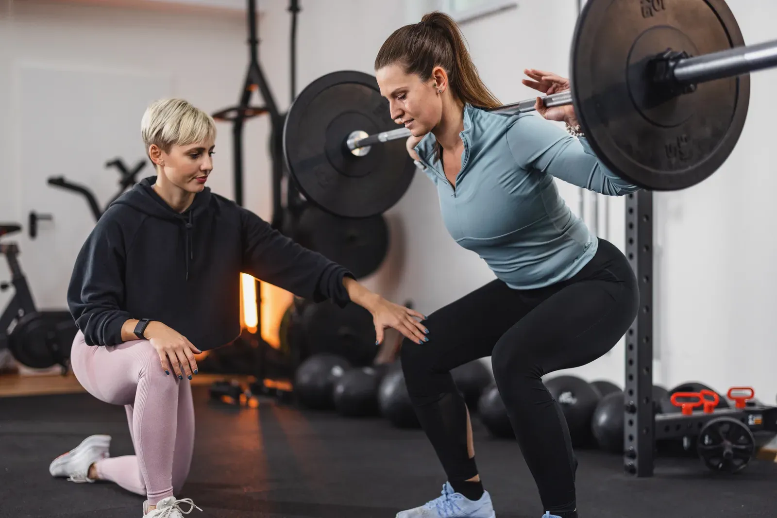 Strength coach guiding a client through a weightlifting progression