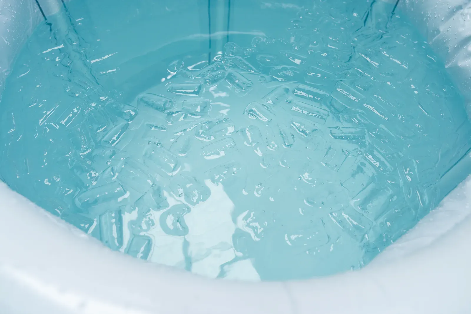 Ice cubes being poured into a tub for a cold plunge recovery session
