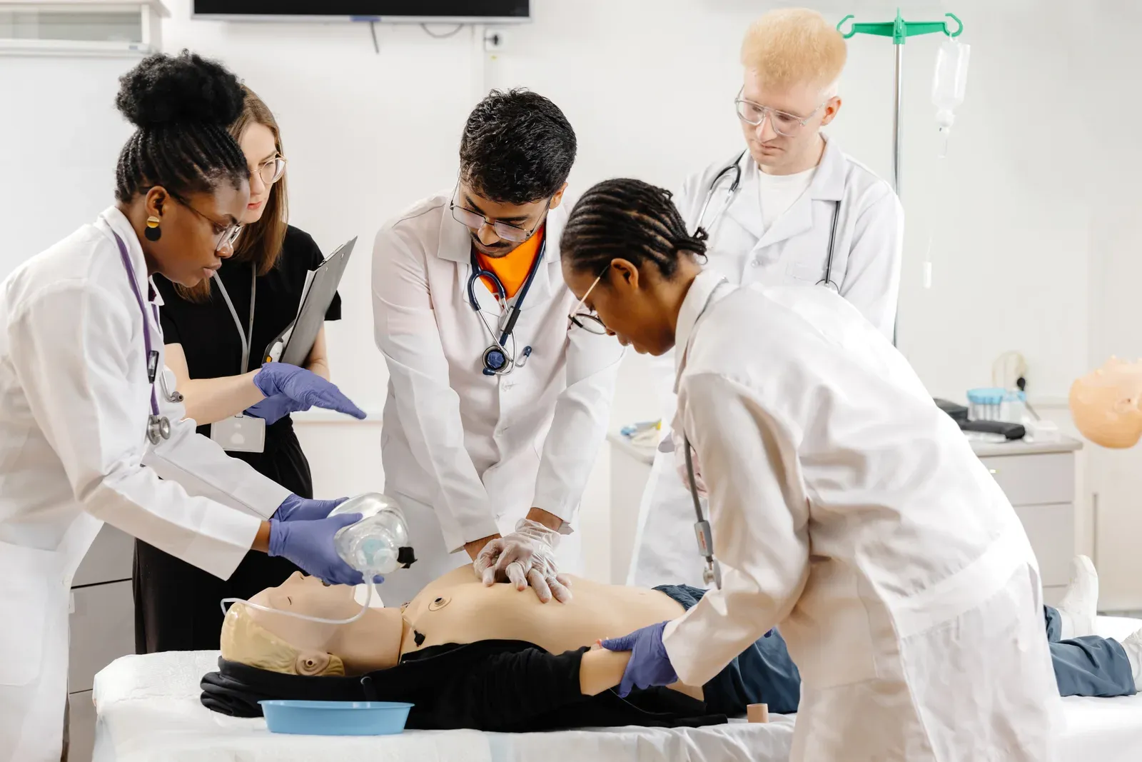 Group of people practicing chest compressions on dummies in first aid training, as with CPR and AED certification