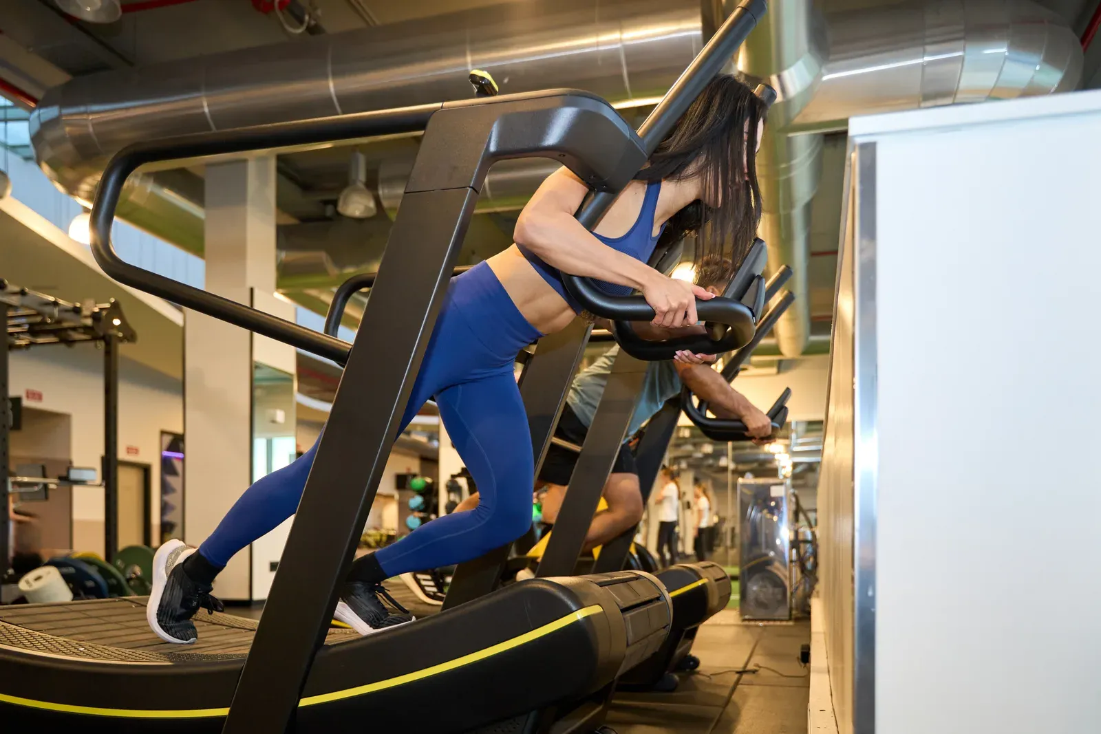 Runner striding on a self-powered curved treadmill in a training studio