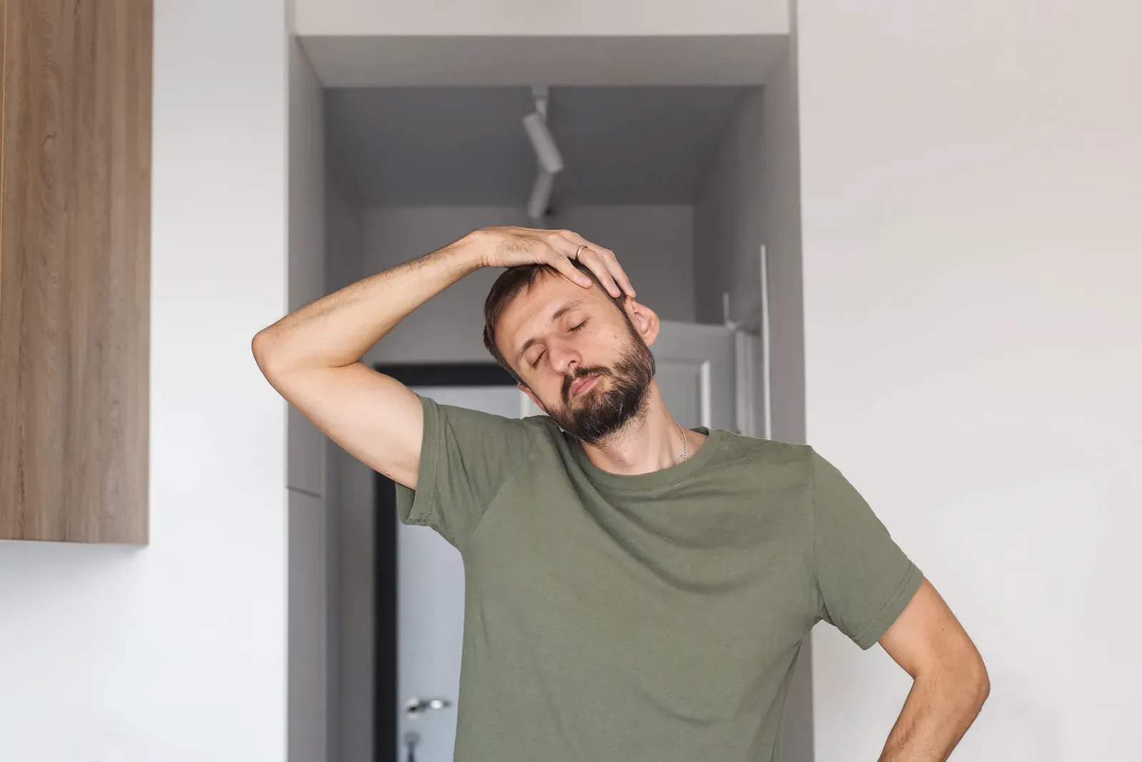 Young man stretching his neck at home with eyes closed, a calm part of a daily mobility routine