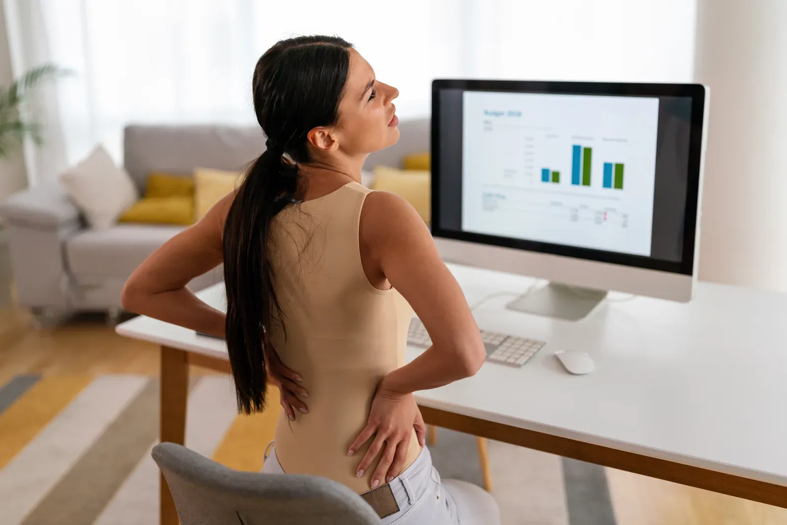 An office worker with rounded shoulders hunched over a desk