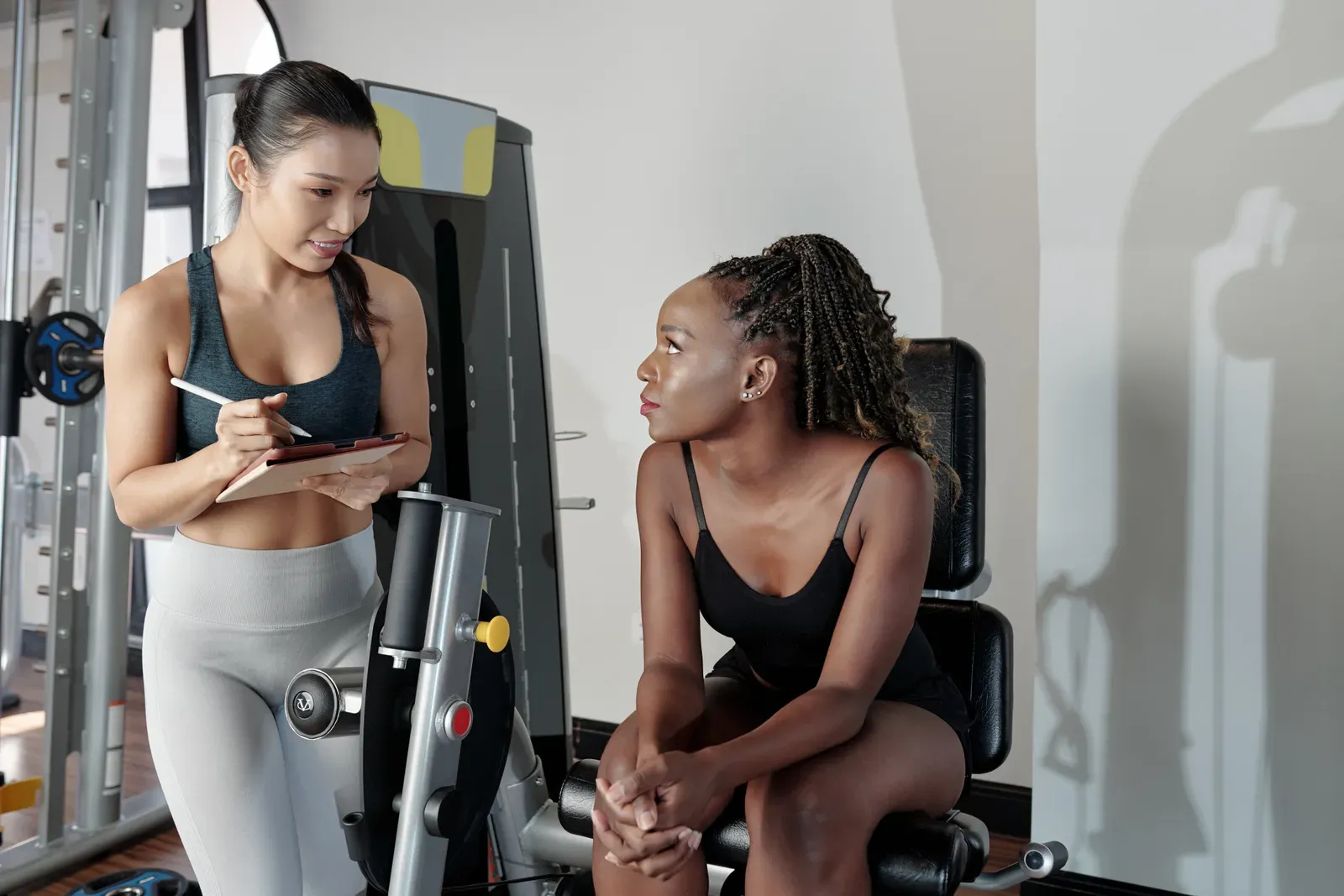 Woman listening to a fitness trainer's recommendations, a conversation that can include asking about discounts