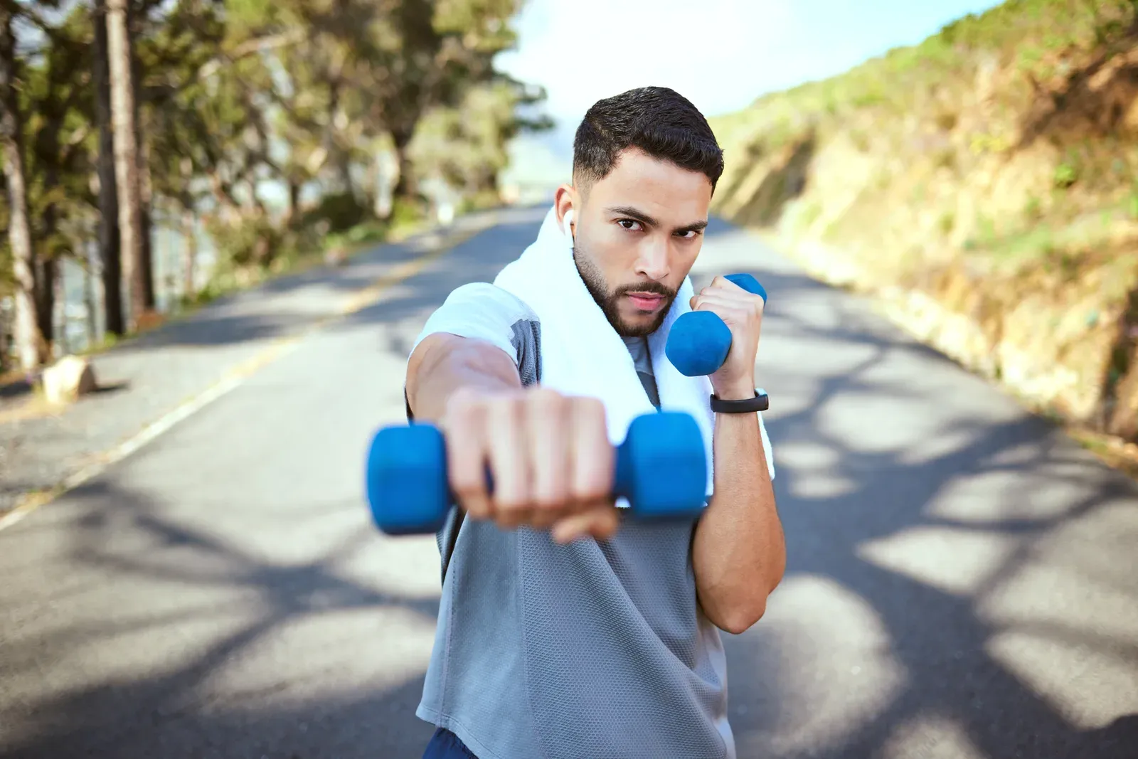 Sporty young man doing dumbbell punches outdoors, a cardio style that raises the question of how much is too much