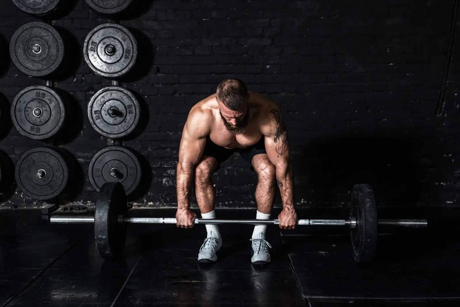 Muscular man holding a heavy barbell at the start of a hard lift, where hydration can affect strength
