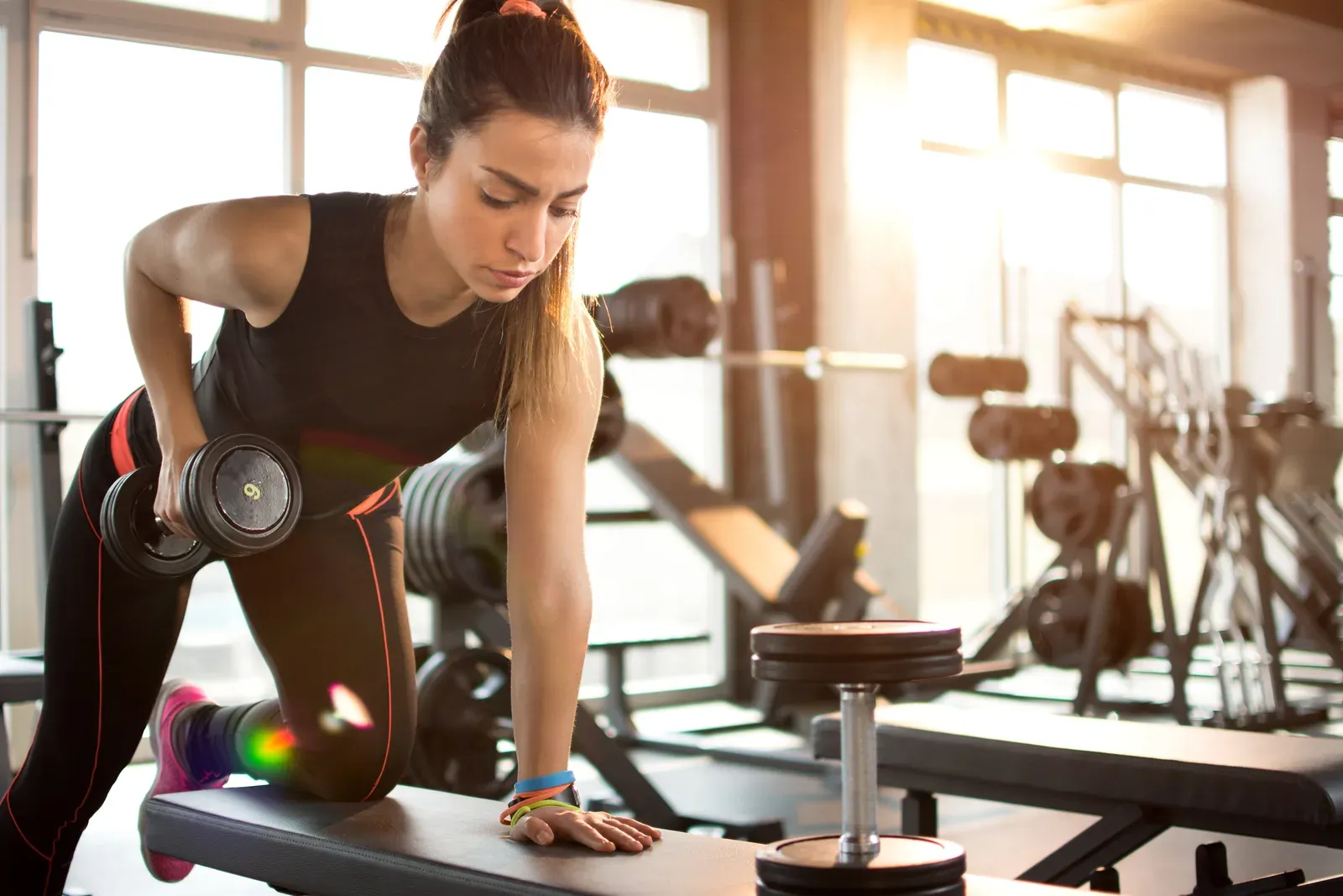 Athlete training with dumbbells in a softly lit gym before sunrise