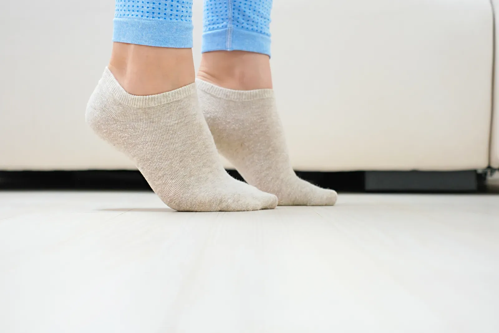 Close view of a woman's legs lifting onto her toes, a calf raise used to rebuild strength after a broken ankle