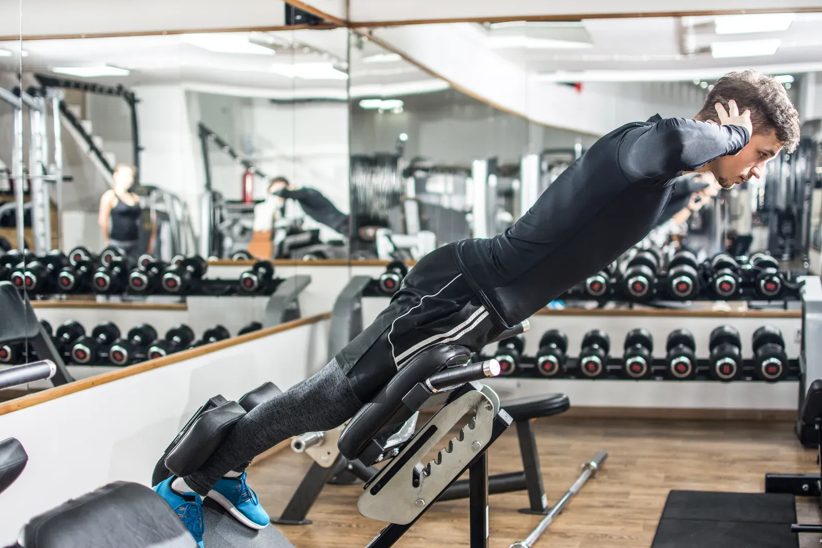 Man performing a back extension on a roman chair at the gym, a movement used for mobility and strength work