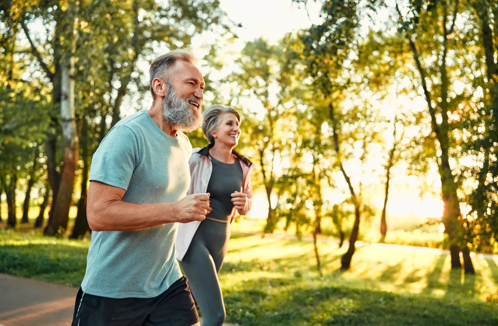 Older couple running through a summer park, keeping body and brain active