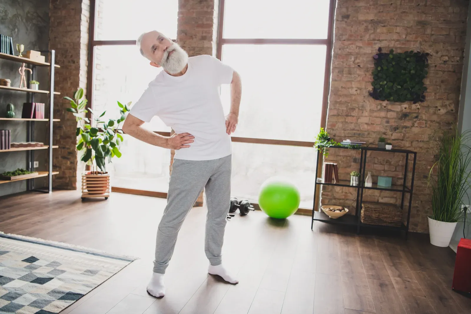 Mature man stretching his spine at home, gentle movement for people managing disc related back pain