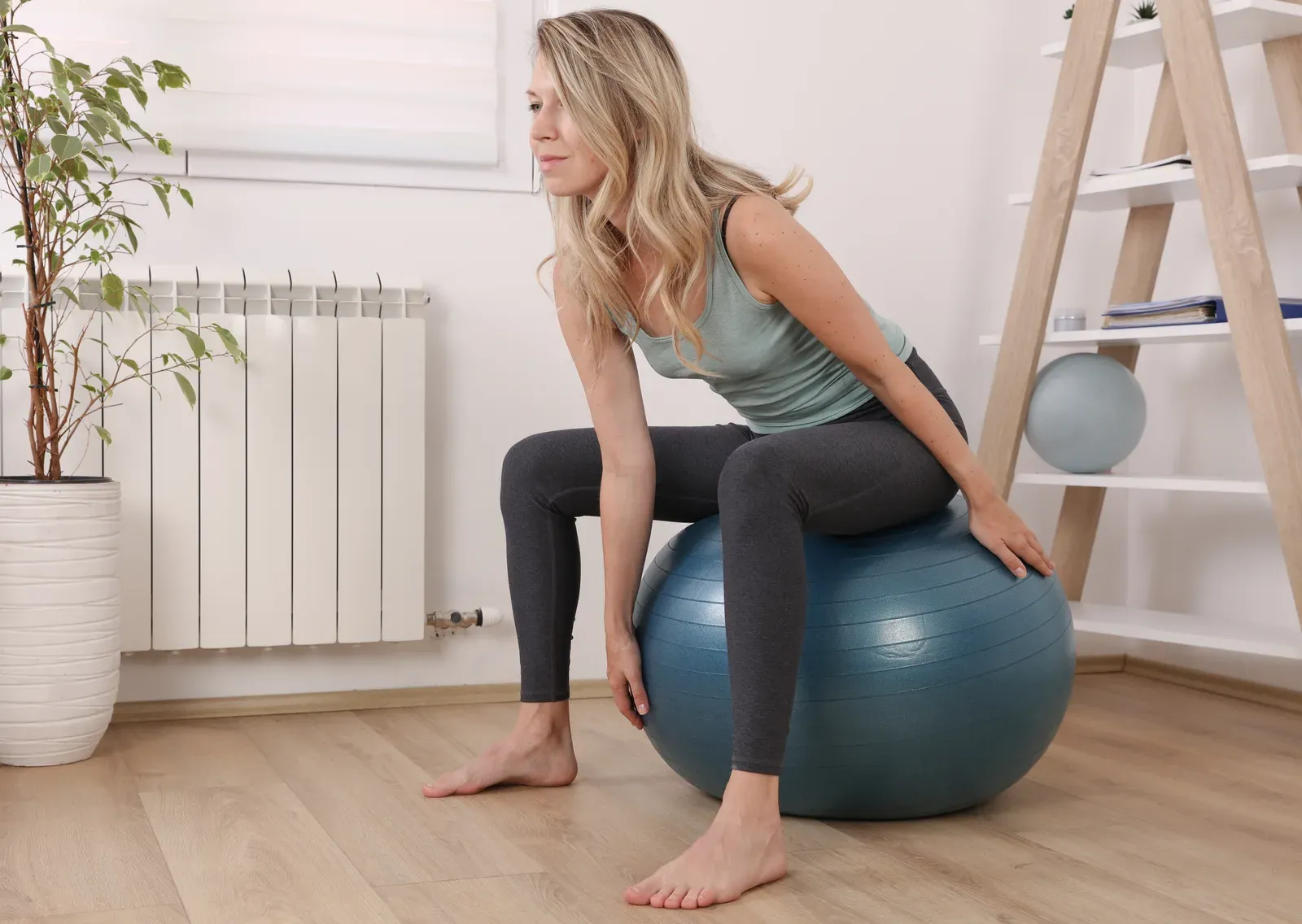 Woman doing a Pilates workout with a fitness ball, balance and breathing exercises that can suit changing pain days