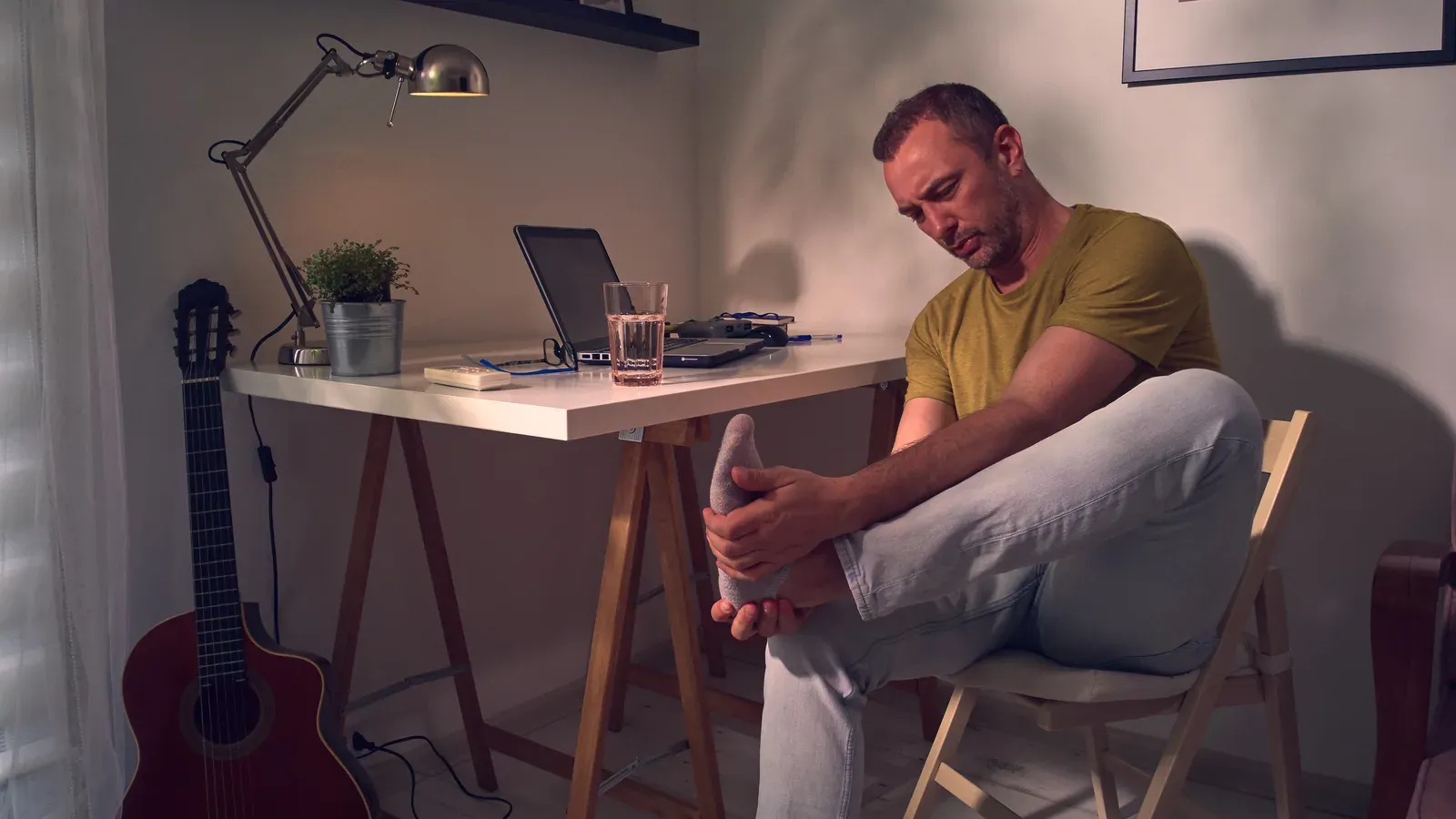Man with ankle and foot pain at home, a reminder to adjust training around gout flares