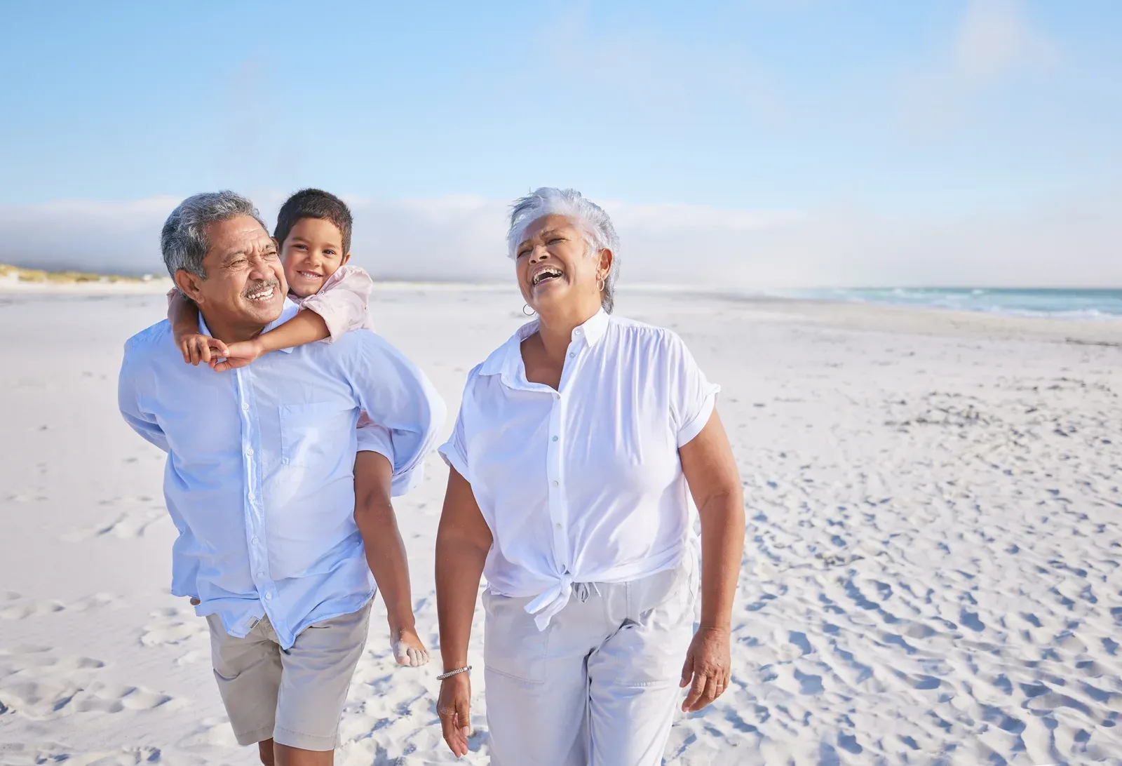 Grandparents walking on the beach with their grandson, who rides piggyback, active time across generations
