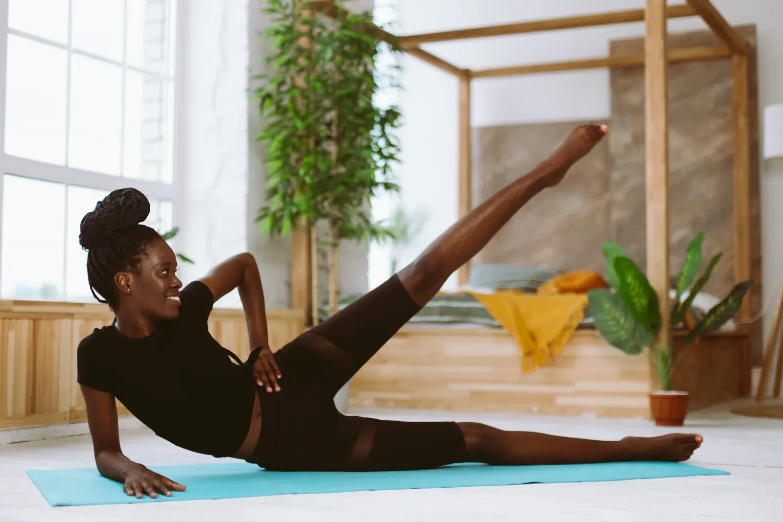 Woman lying on her side raising a leg on a gym mat, a glute strengthening move for hip bursitis