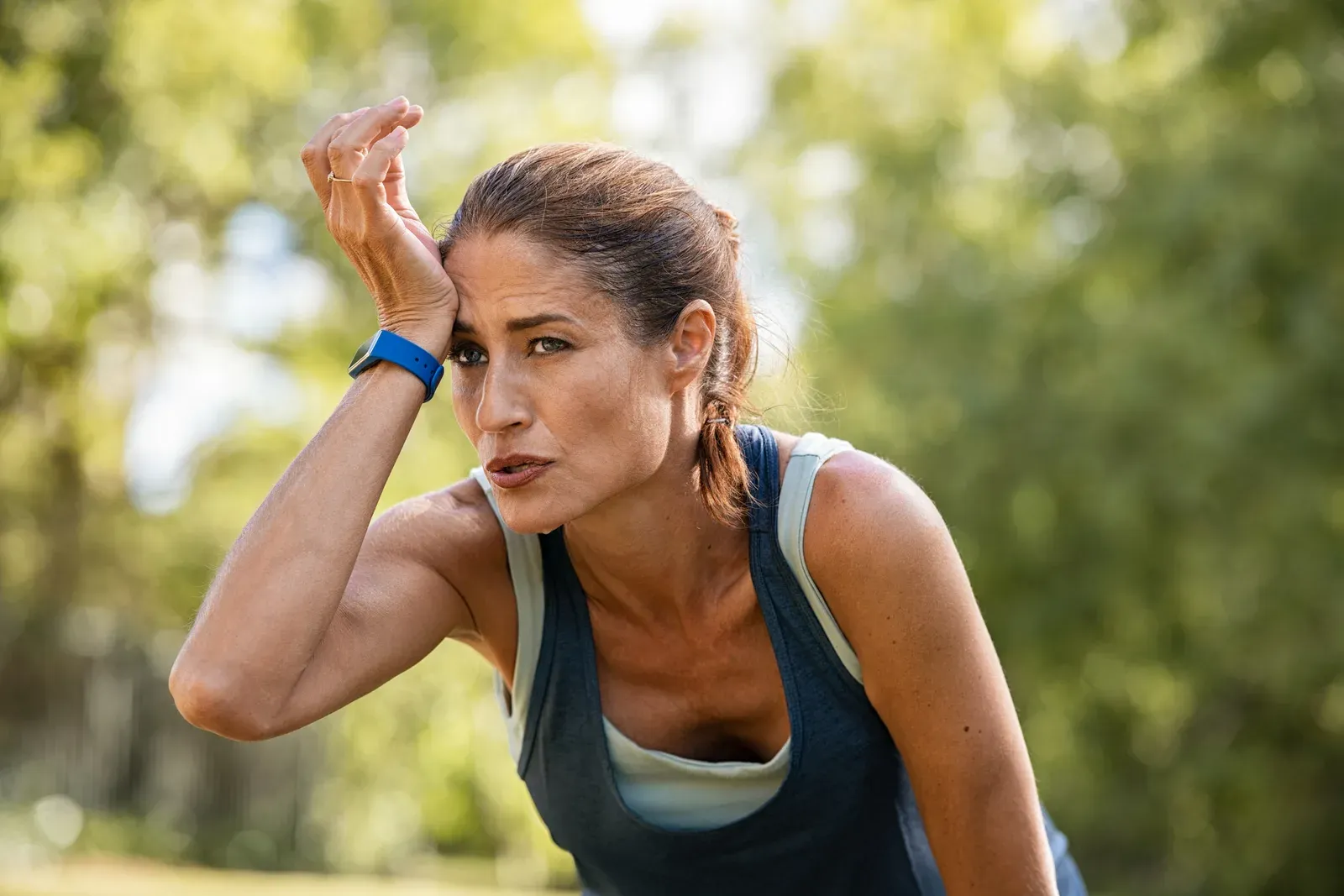 Tired mature runner wiping sweat after a workout in the park, a cue to train smart with low iron