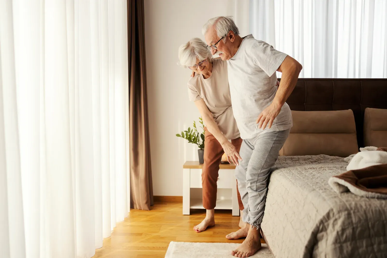 Senior woman helping her husband get up from bed in the morning, a daily lift that safe technique supports