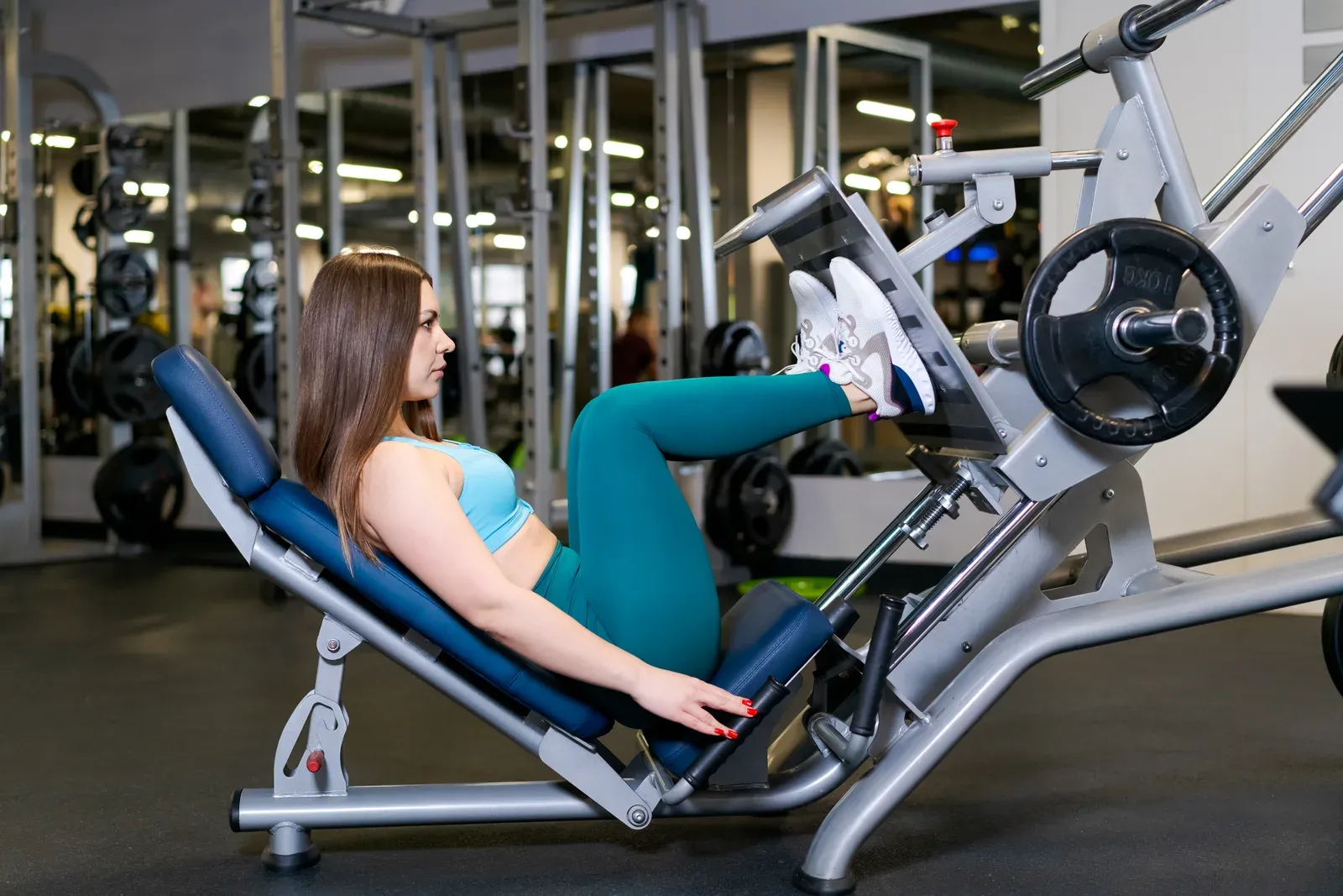 Woman exercising on a leg press machine, a supported way to train the legs around a stiff big toe