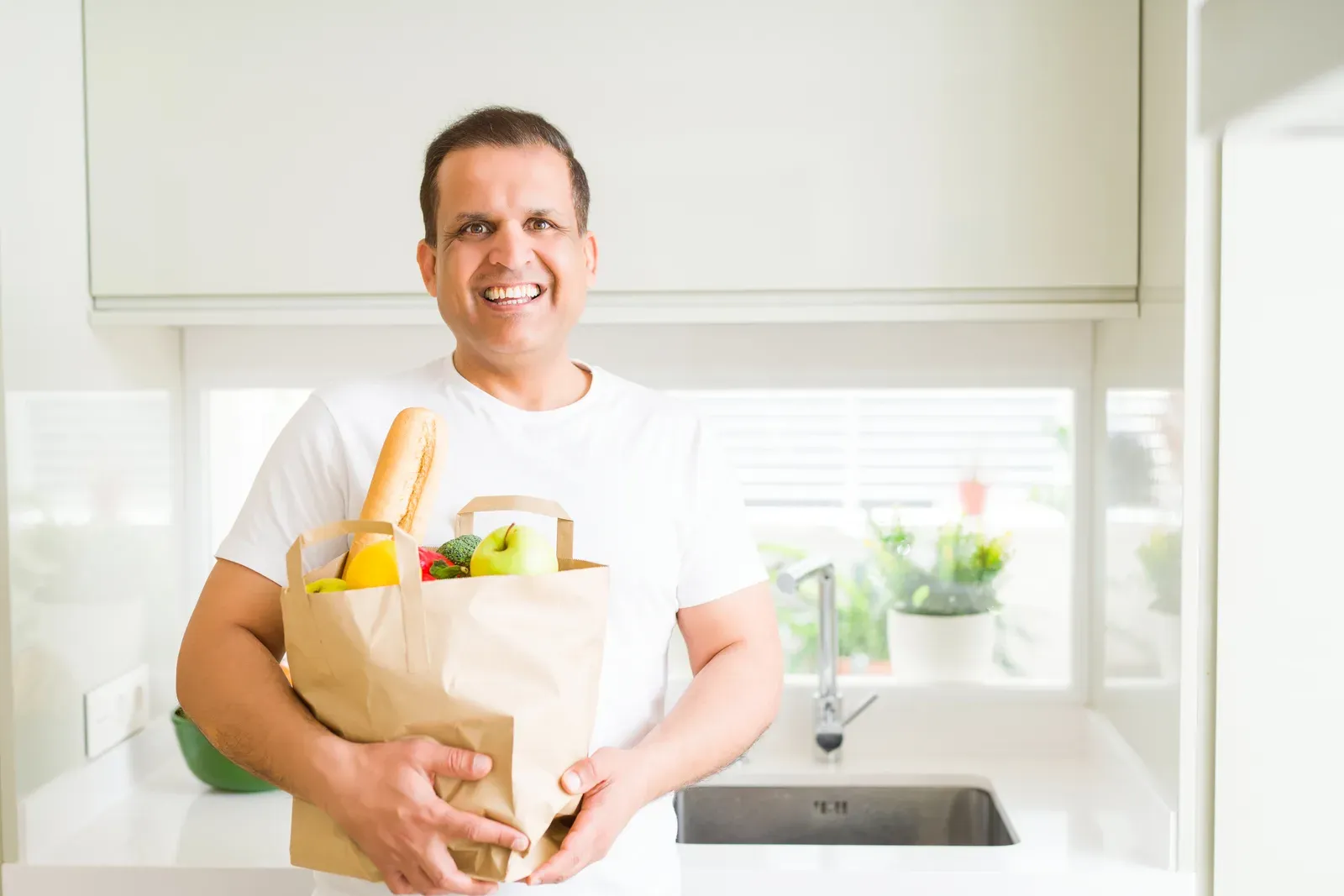 Middle age man holding a grocery bag full of vegetables at home, an everyday carry that training makes easier