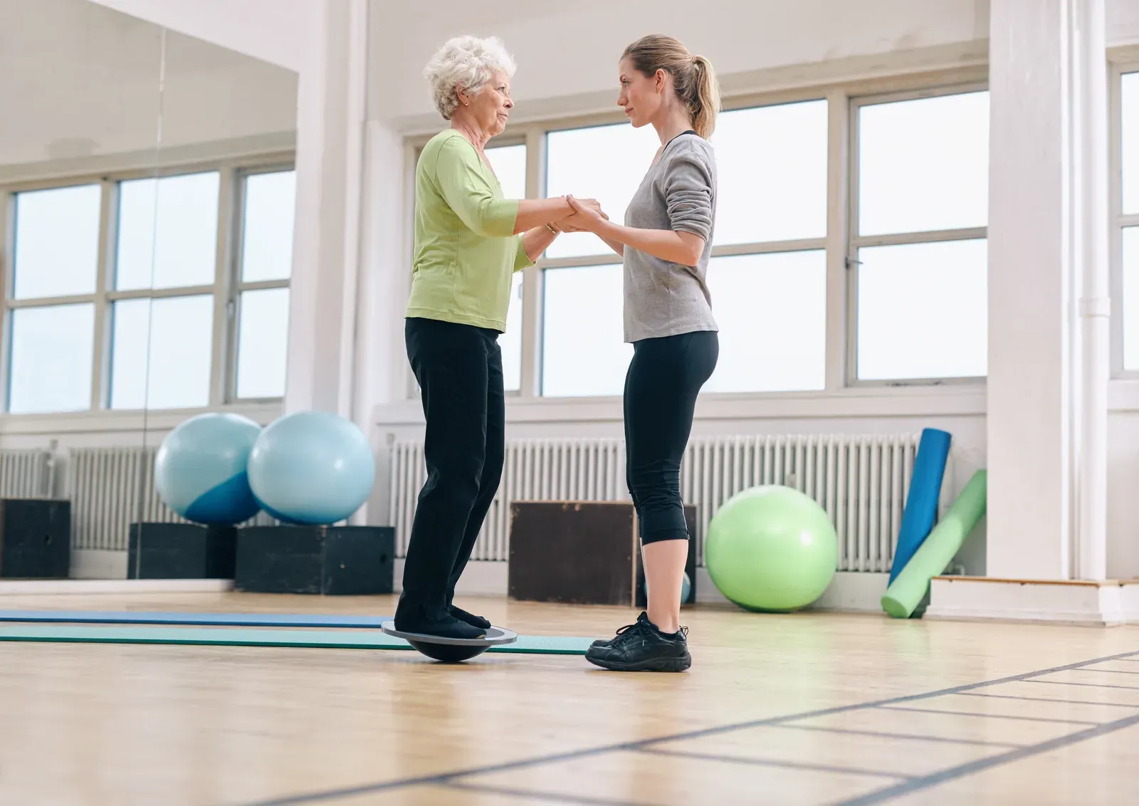 A coach supporting an older adult during a step-up exercise for fall prevention