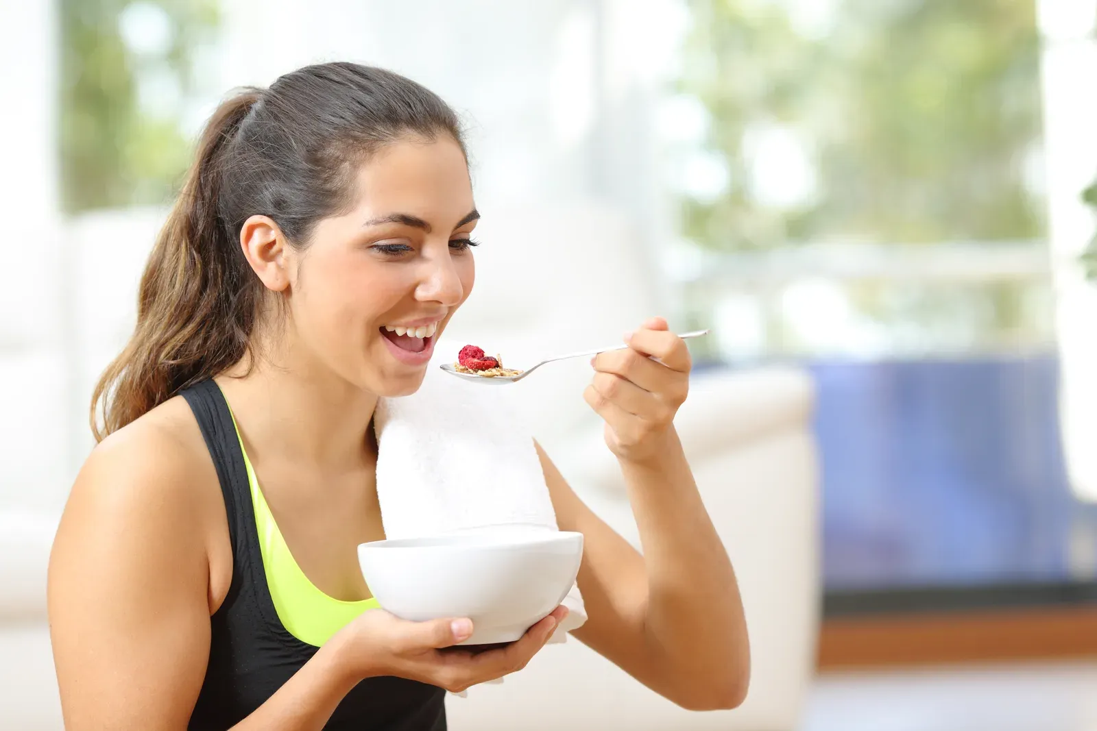 Sportswoman eating cereal after a workout at home, a post-training meal that fits the fasted training debate