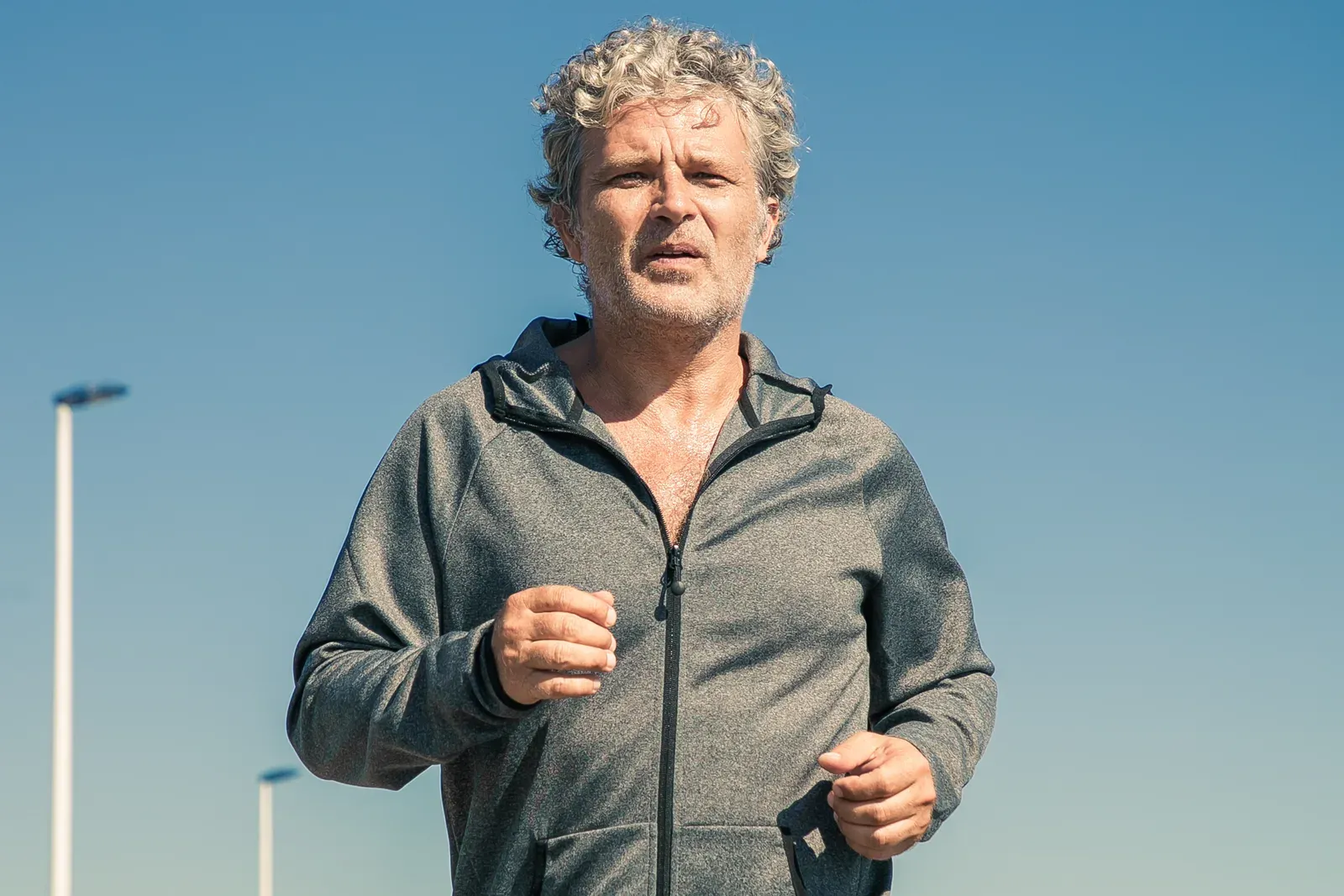 Tired grey haired man in a sports jacket jogging outside, a starting point for men over 40 losing weight