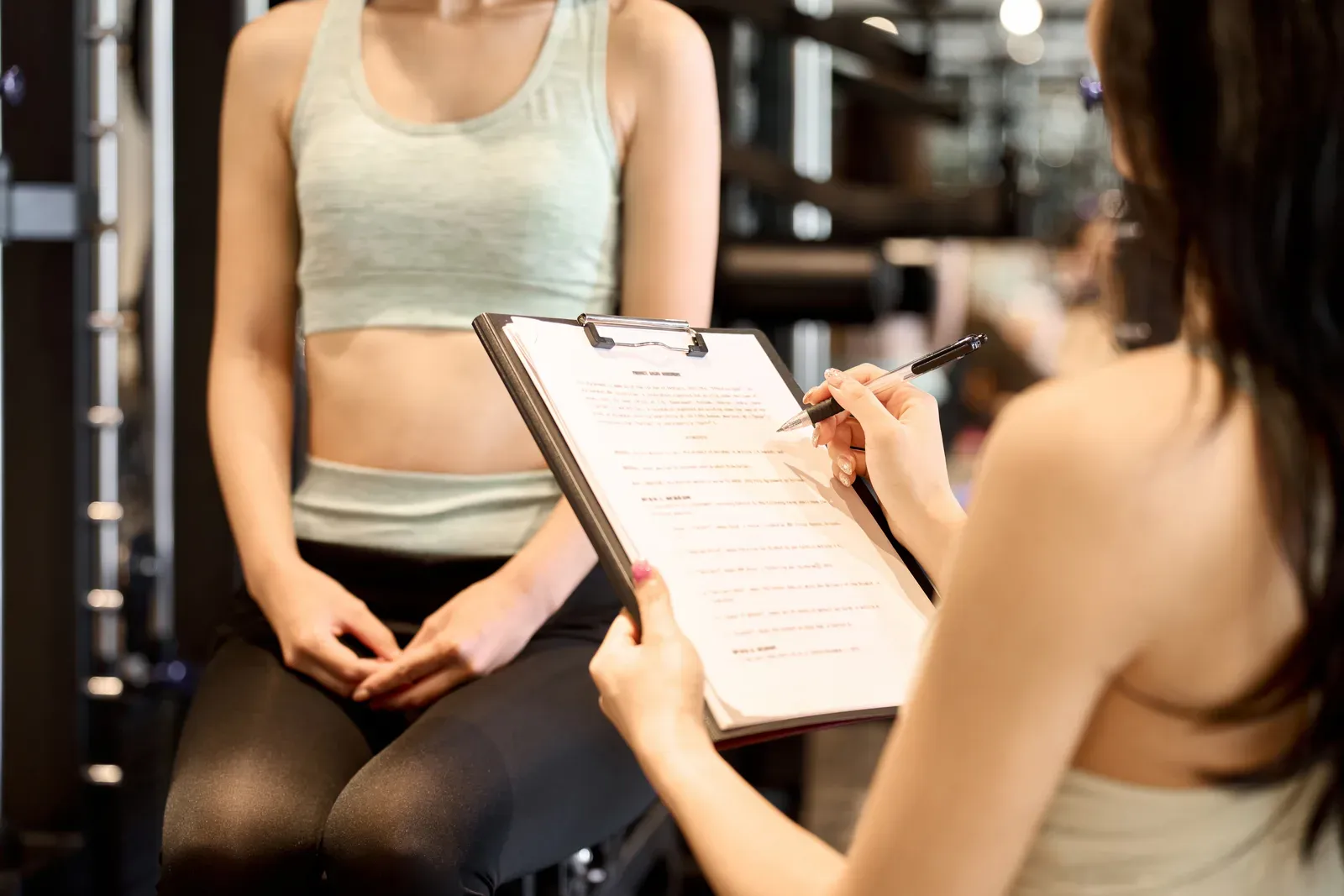 Fitness coach reviewing a clipboard of client paperwork during a consultation